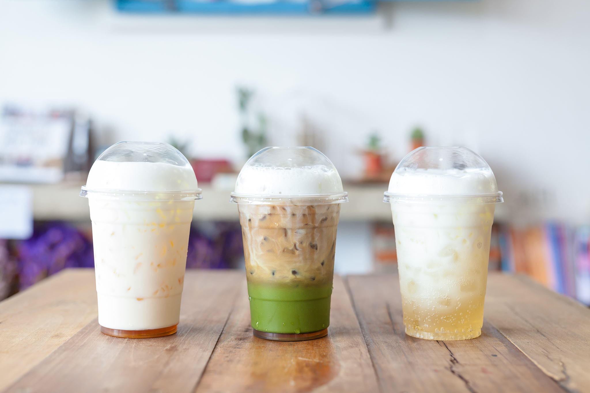 一个俯拍的淡粉色奶茶饮料带有白色奶盖顶部有梅花花瓣这段话用英语地道的表达出来