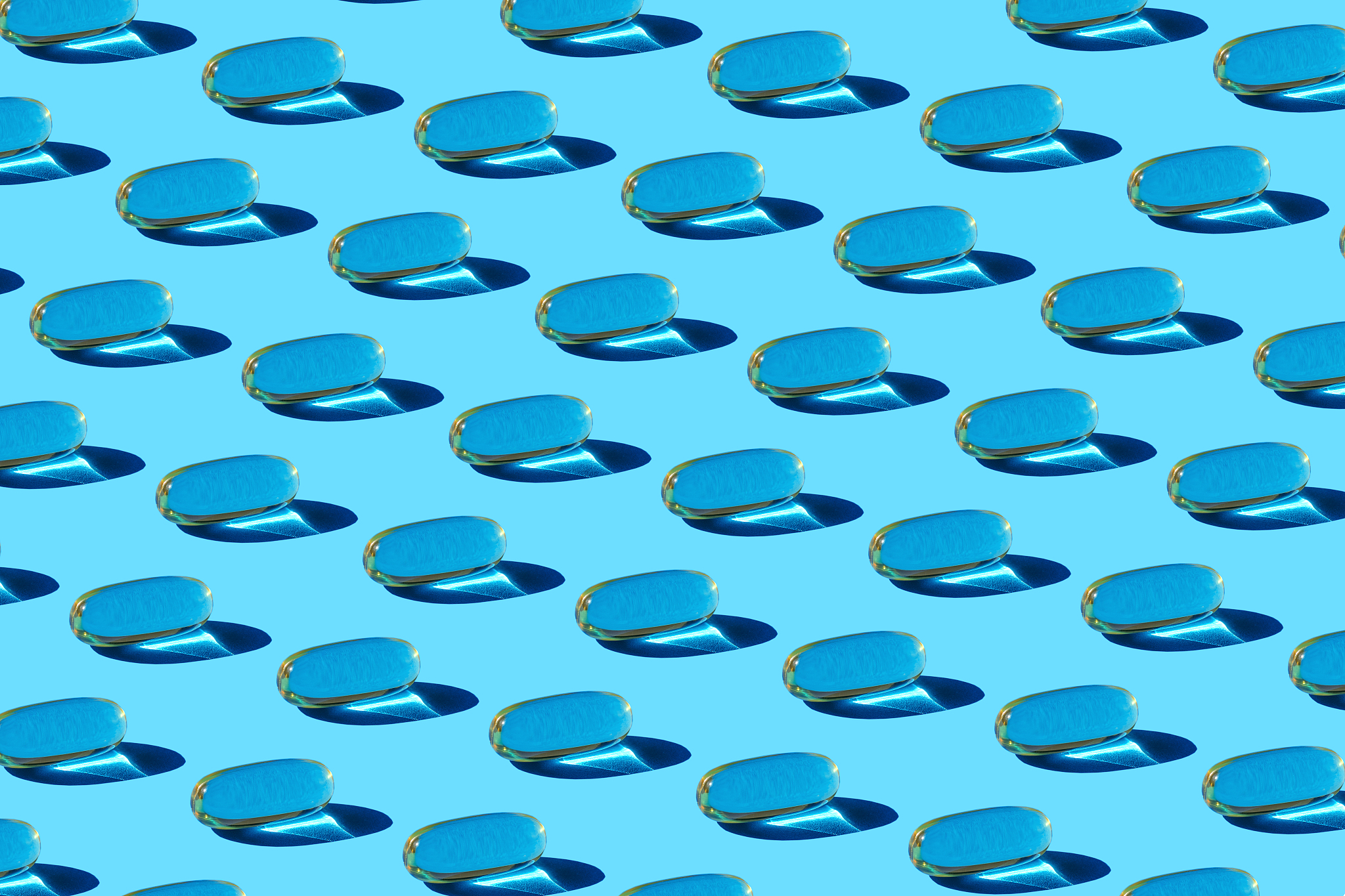glass with fish oil pills on the blue background