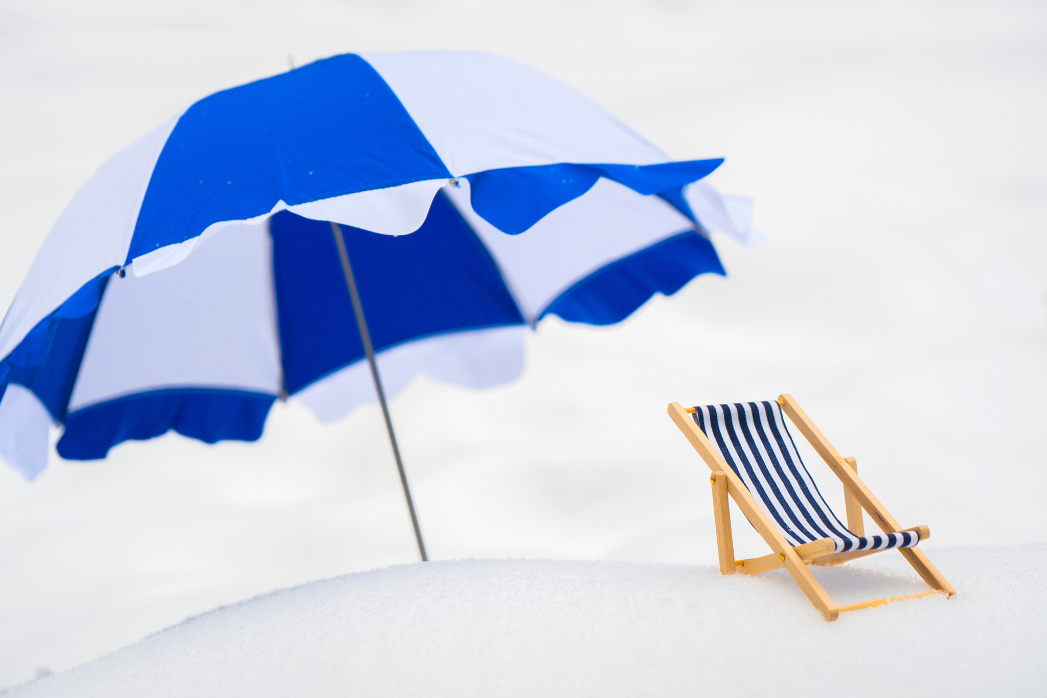blue, wooden, striped wooden beach chair in the snow