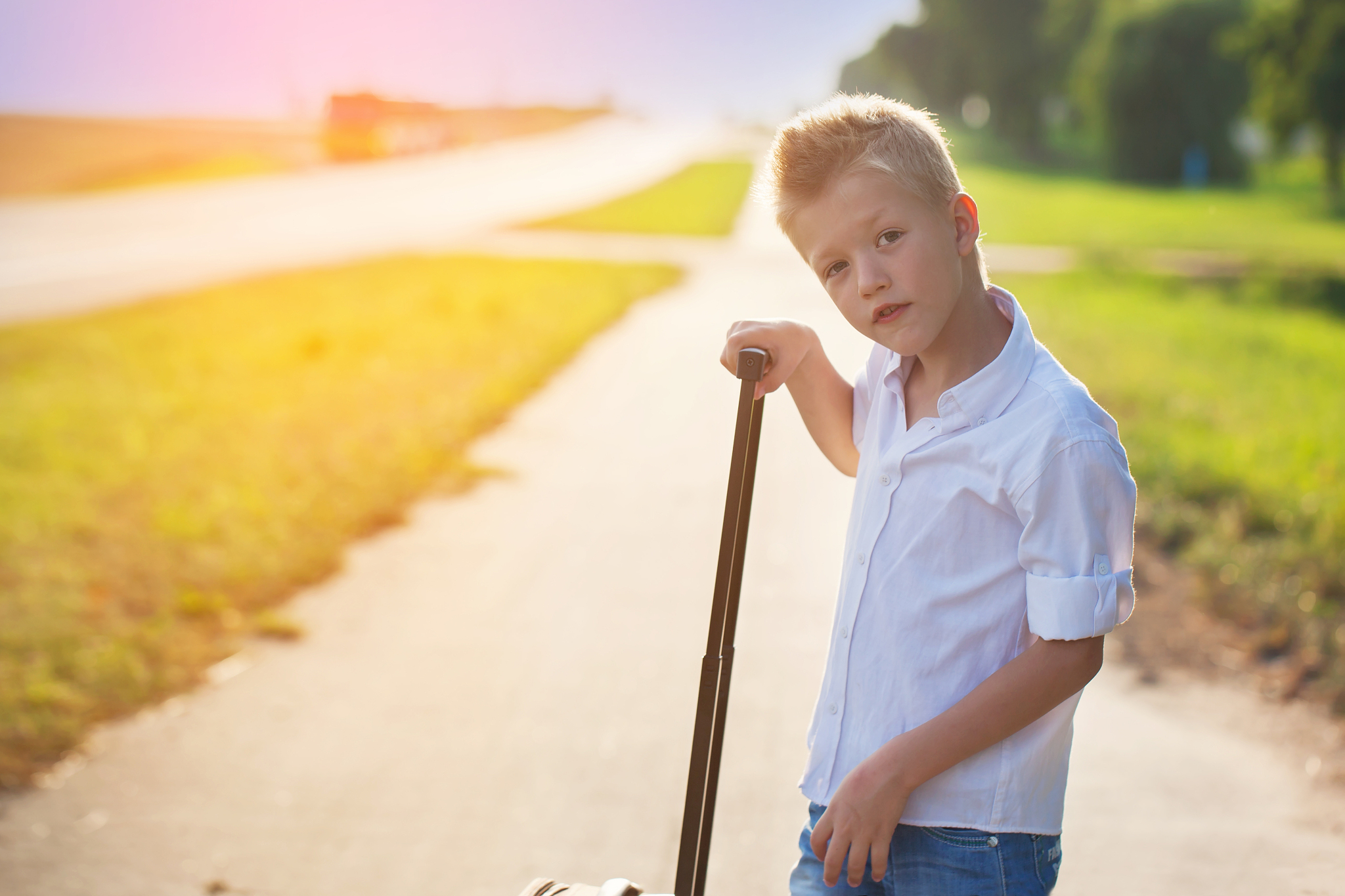 portrait of  boy  holds the handle of a suitcase