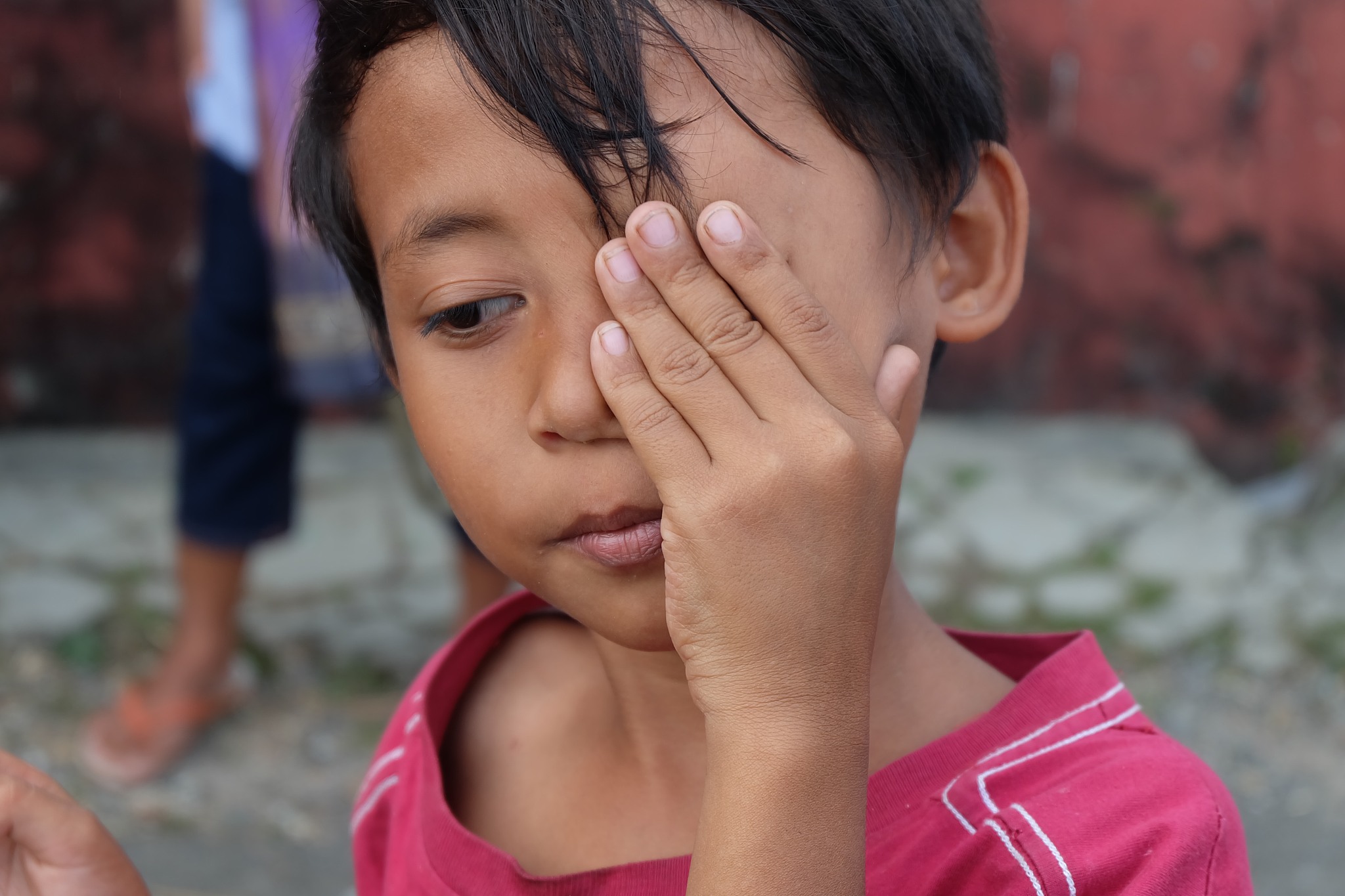 close-up of cute boy with hand on face looking away while standi
