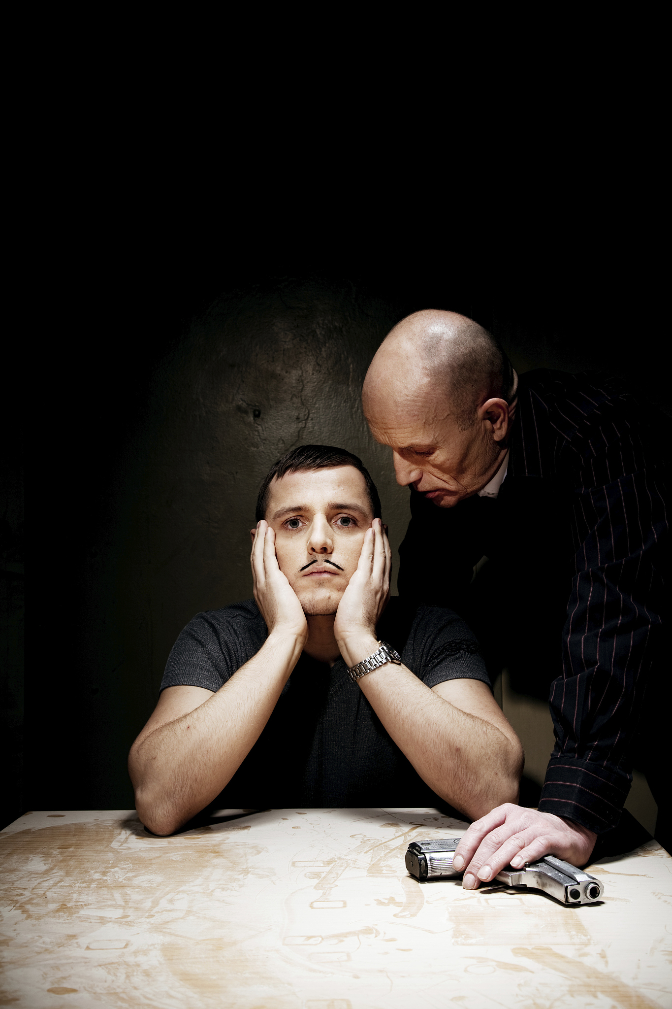 man looking bored while being interrogated by male holding gun
