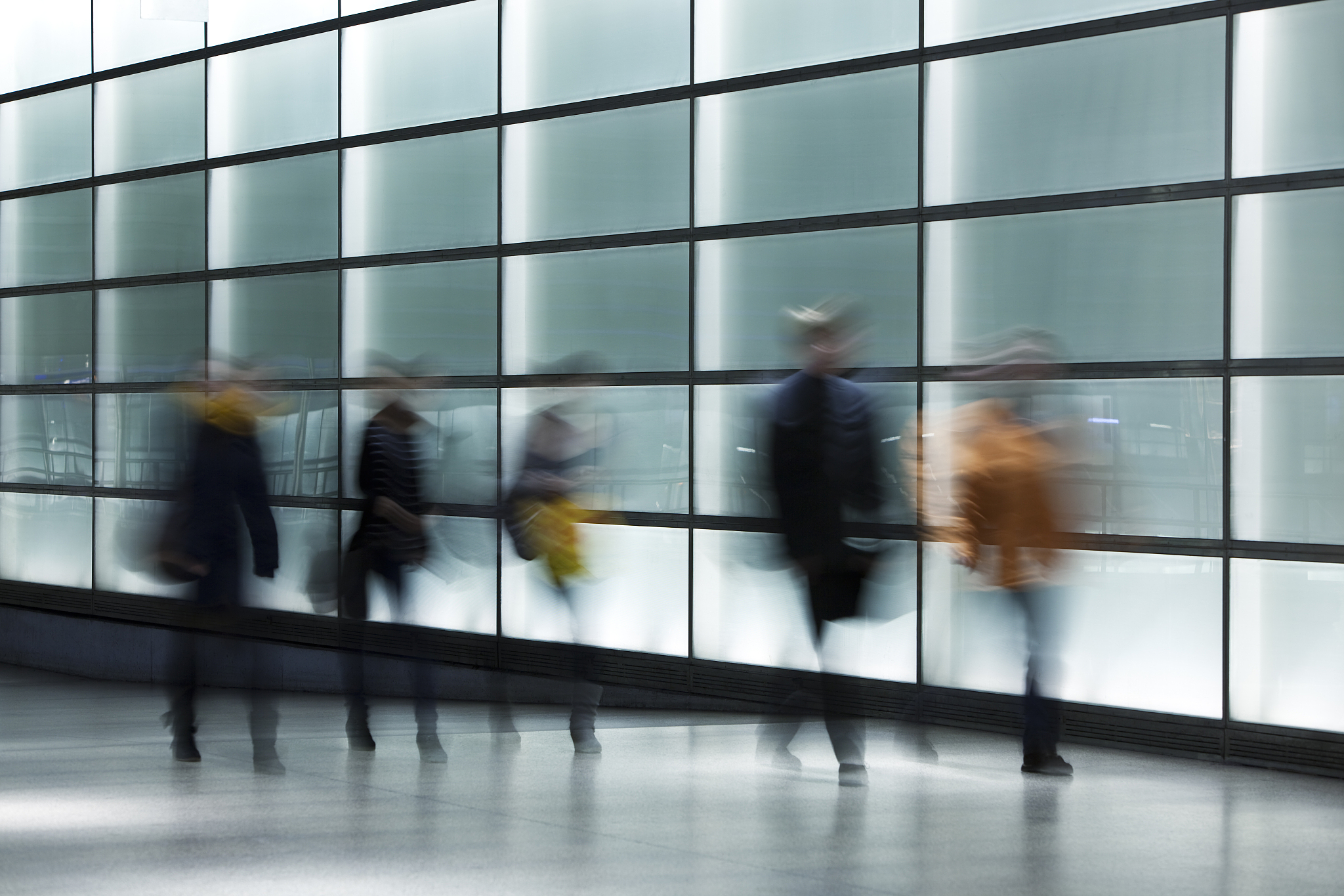 people walking against illuminated glass wall