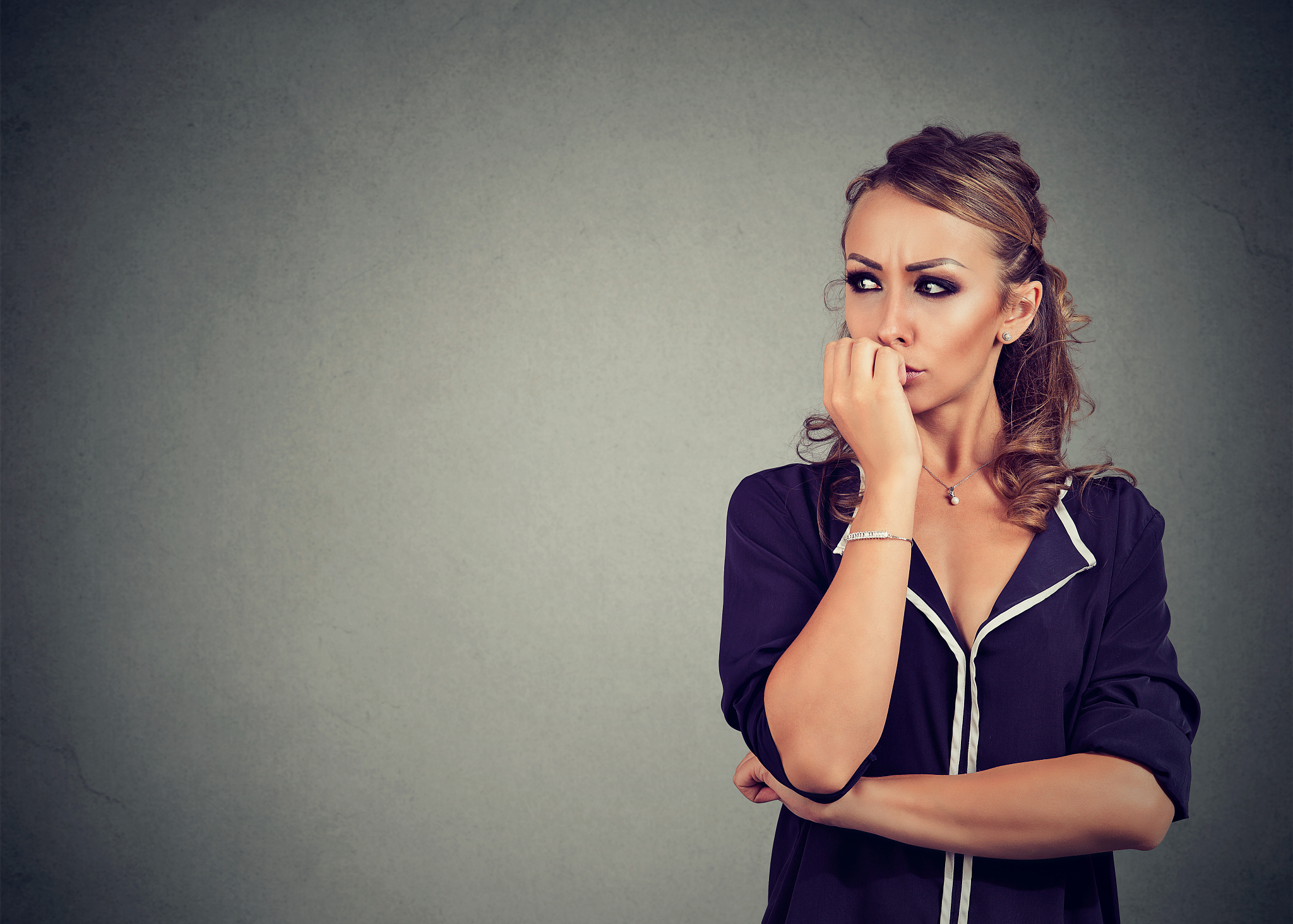preoccupied anxious young woman biting her fingernails looking t
