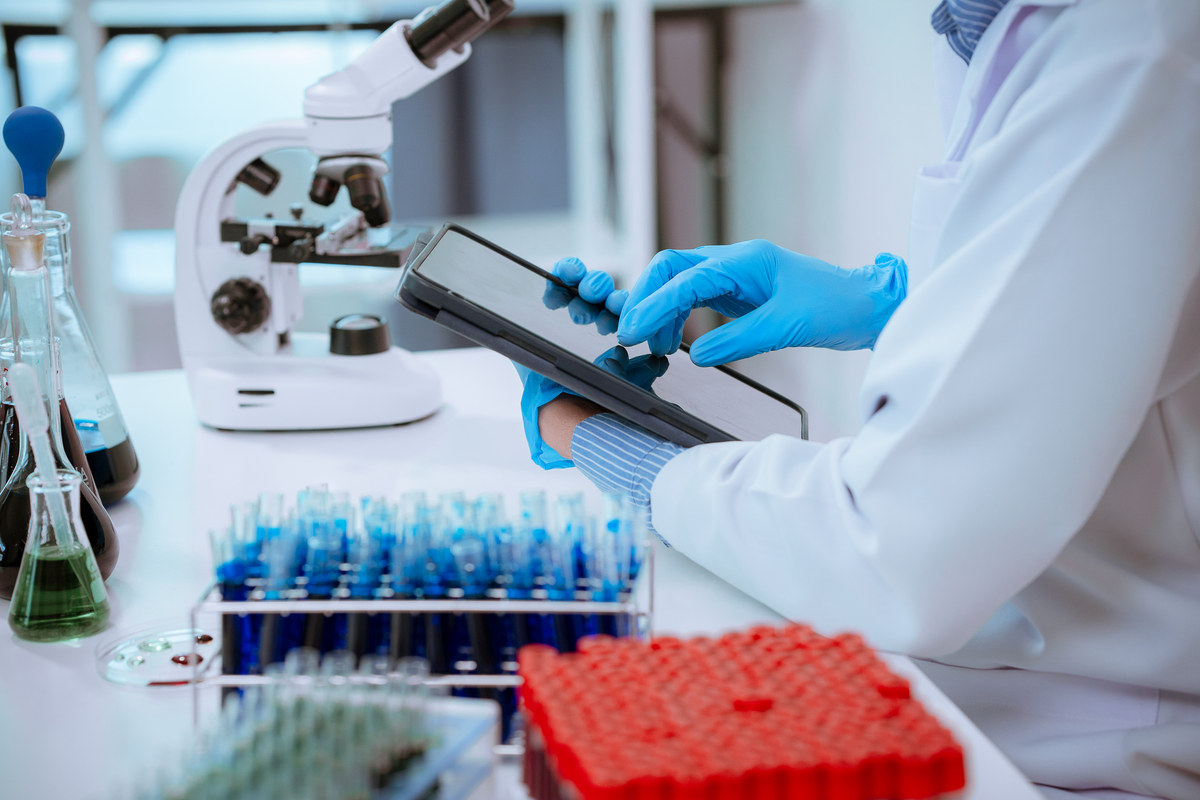 科学:医生在实验室拿起一支试管进行分析,技术人员穿