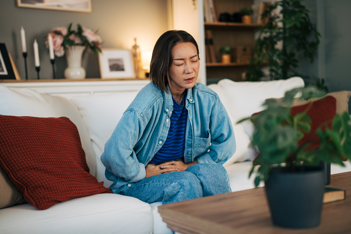 腹痛的亚洲女性捂着肚子