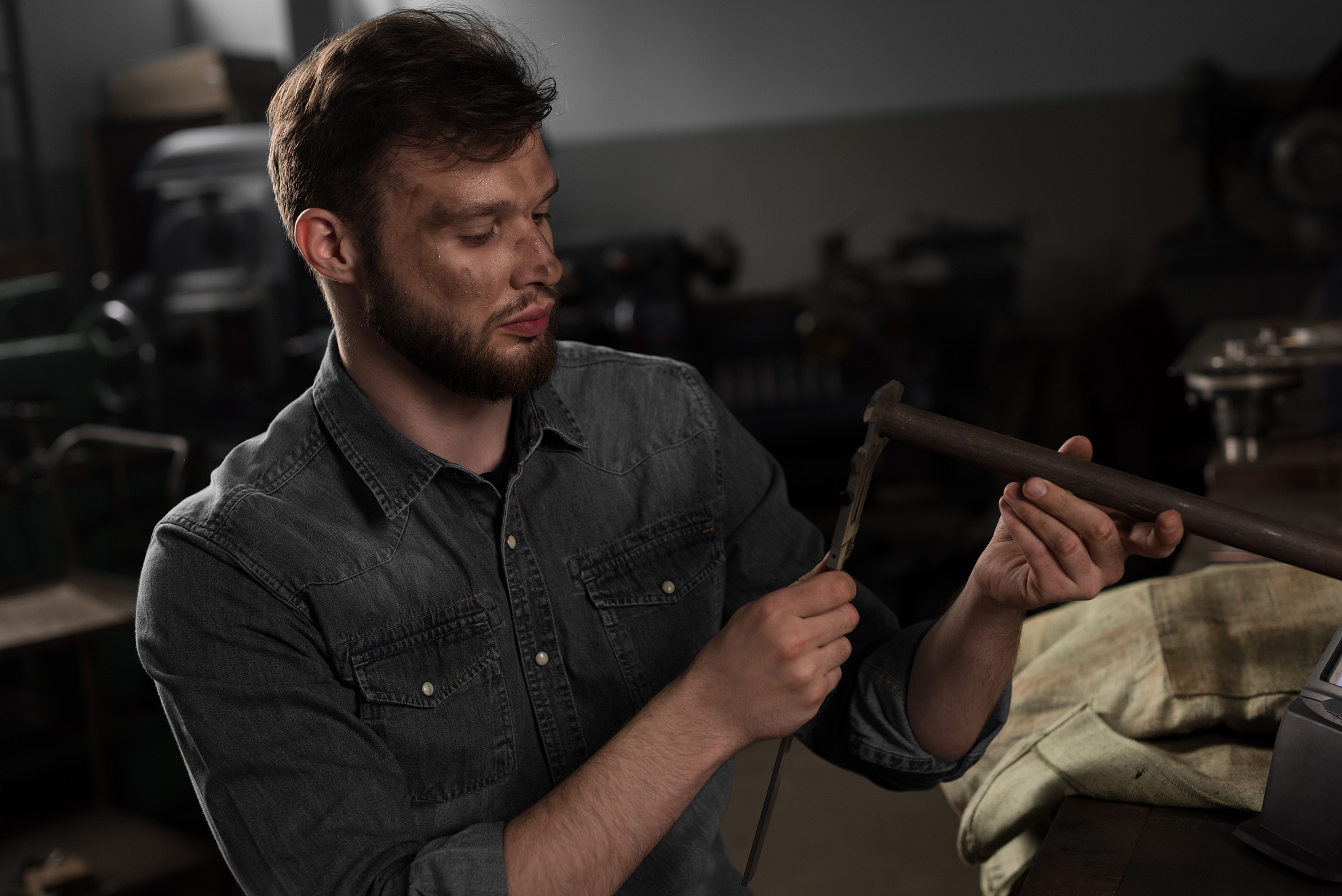 young male worker measuring metal part at factory