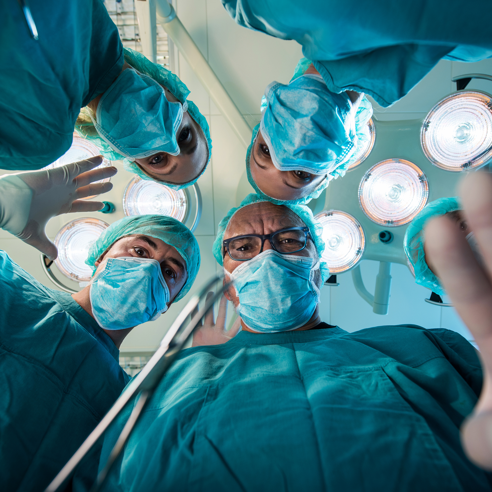 below view of team of surgeons performing a surgery.