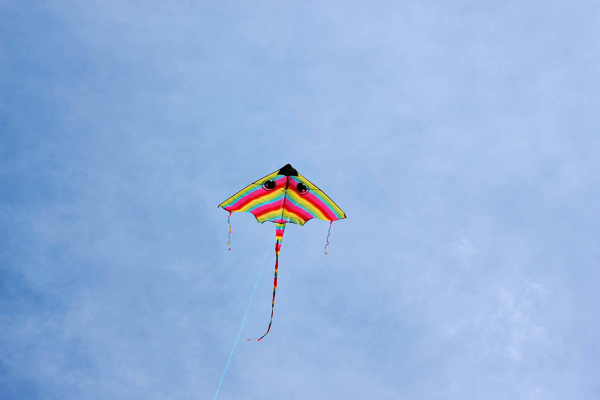 bright kite flying in the clouds and blue sky in the background.