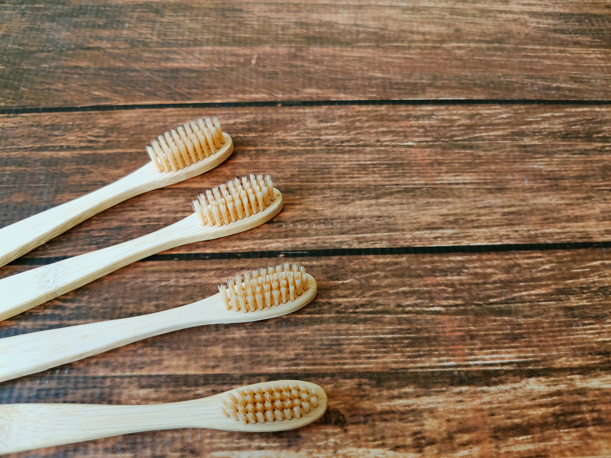 a family set of four wooden toothbrushes on wooden background wi