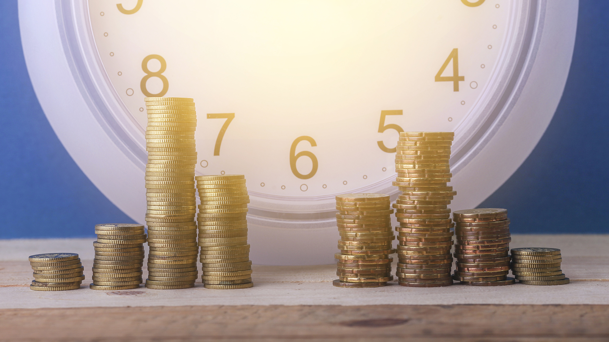 stacked gold coin, white clock and blue background, financing co