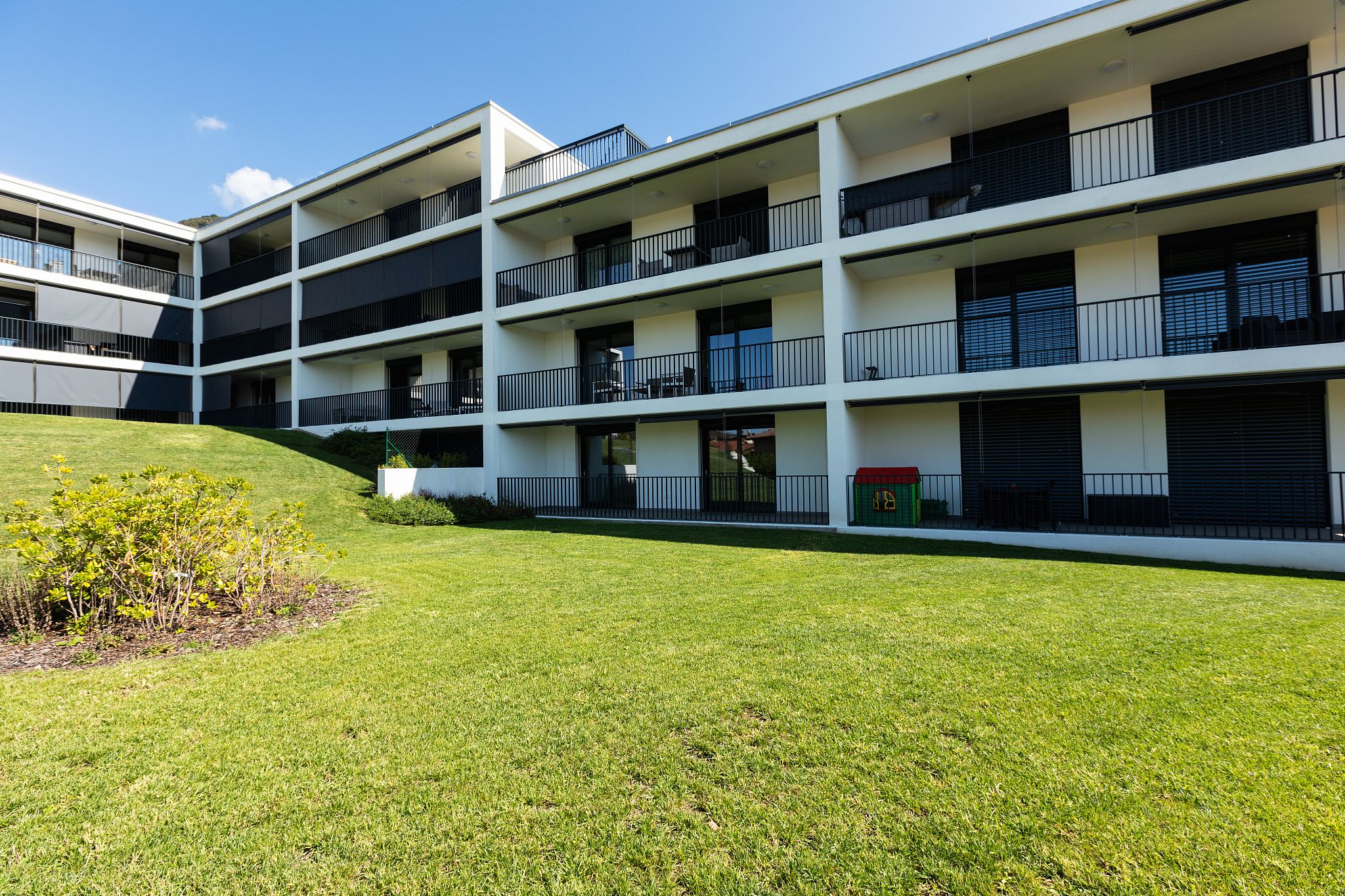 exterior modern white condominium building with lots of lawn,