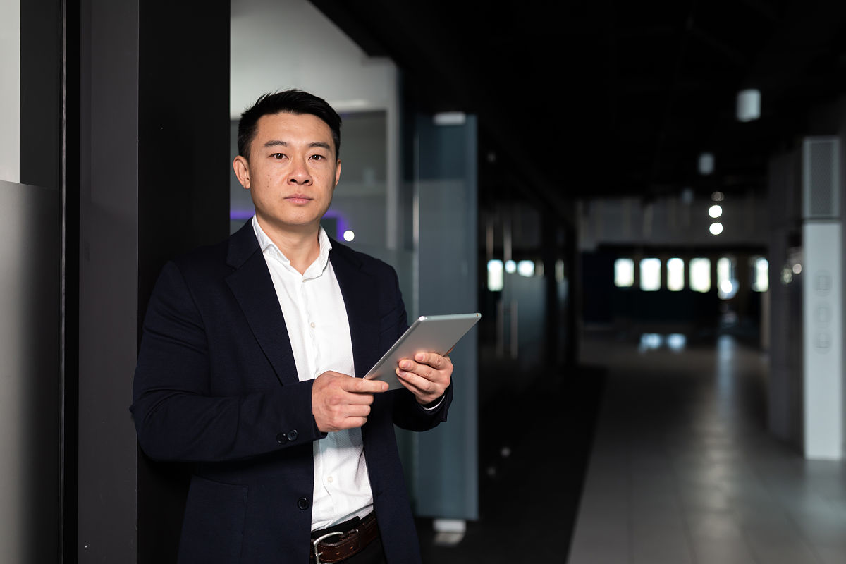 在现代的办公室里,认真的亚洲男性专注于用平板电脑工作