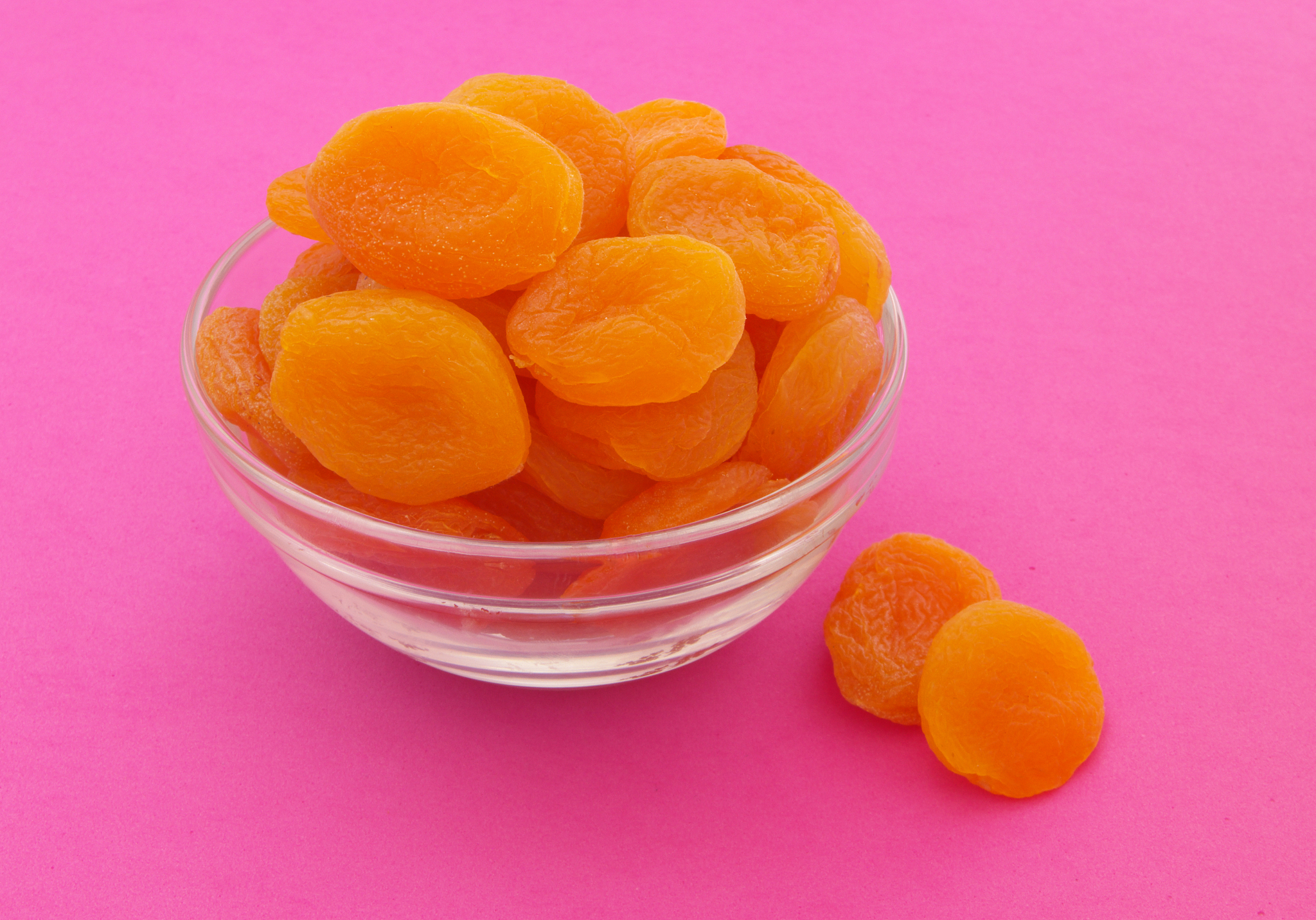 heap of dried apricots fruits on pink background