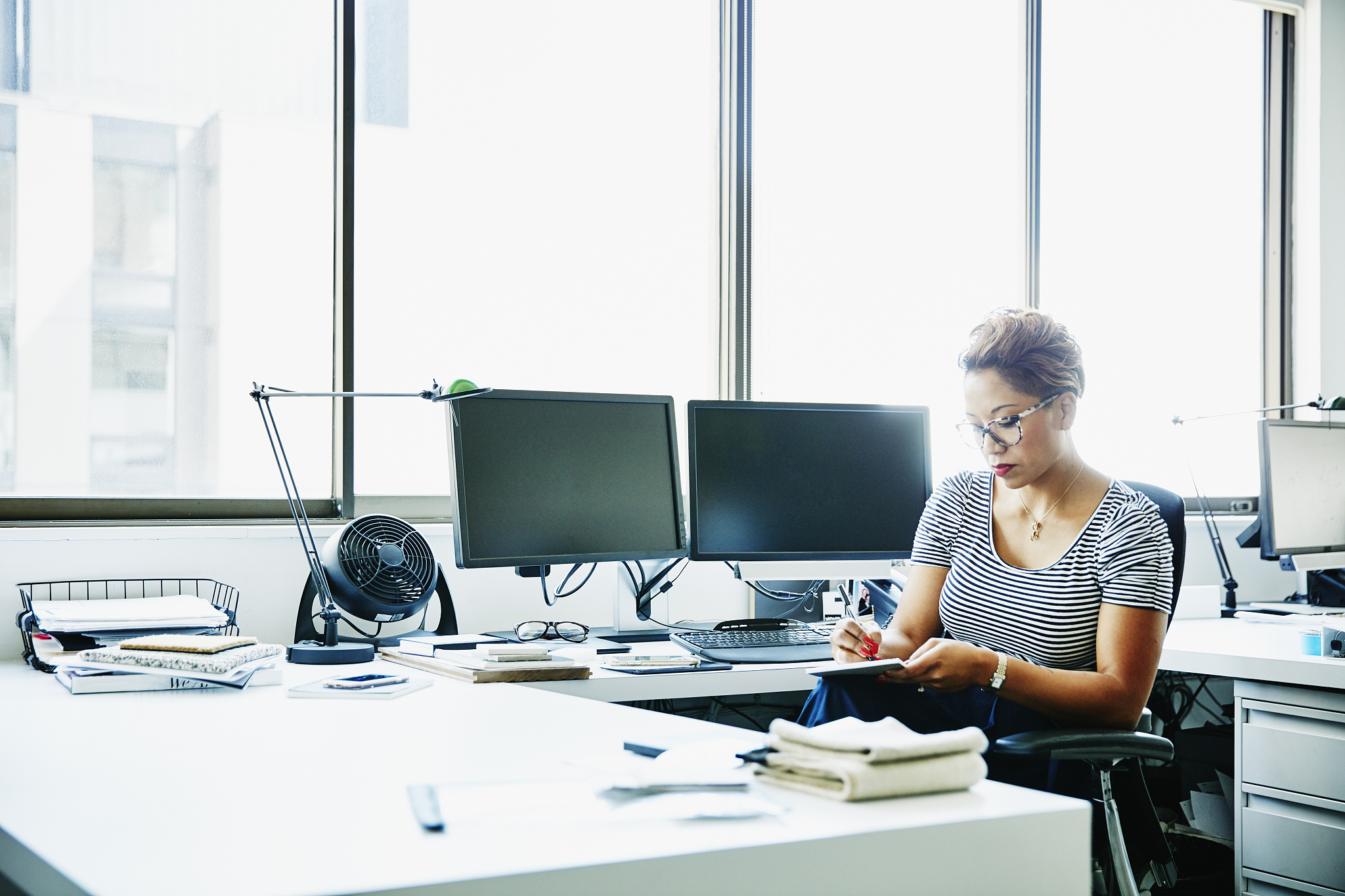 businesswoman taking notes at office workstation