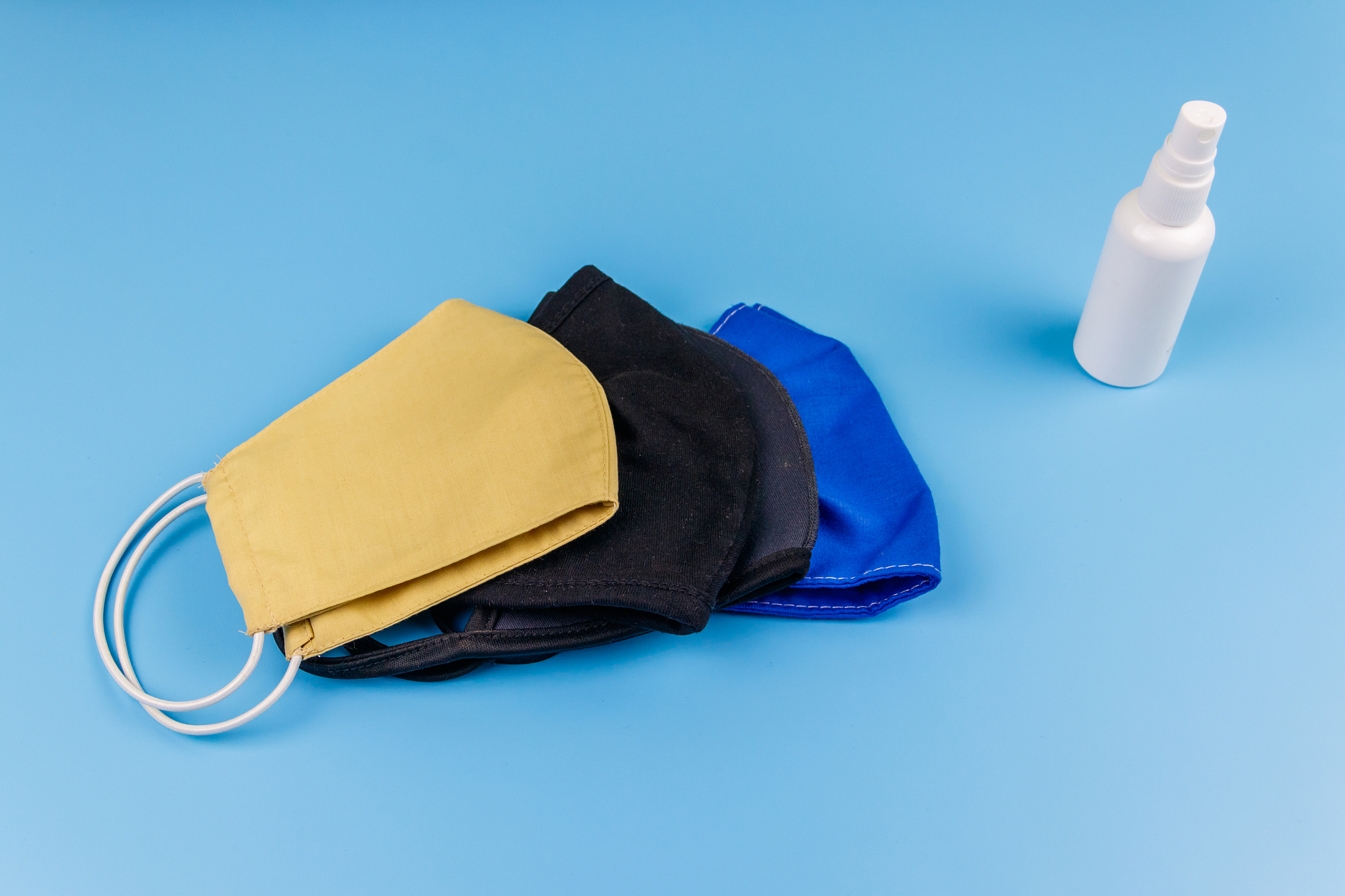 set of reusable fabric masks and hand sanitizer on blue backgrou