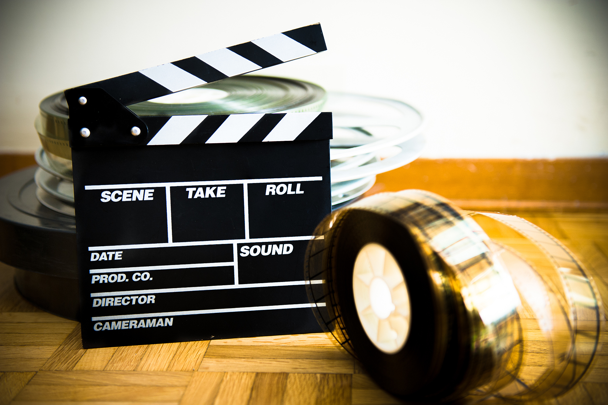 movie clapperboard and 35 mm film reel on wooden floor