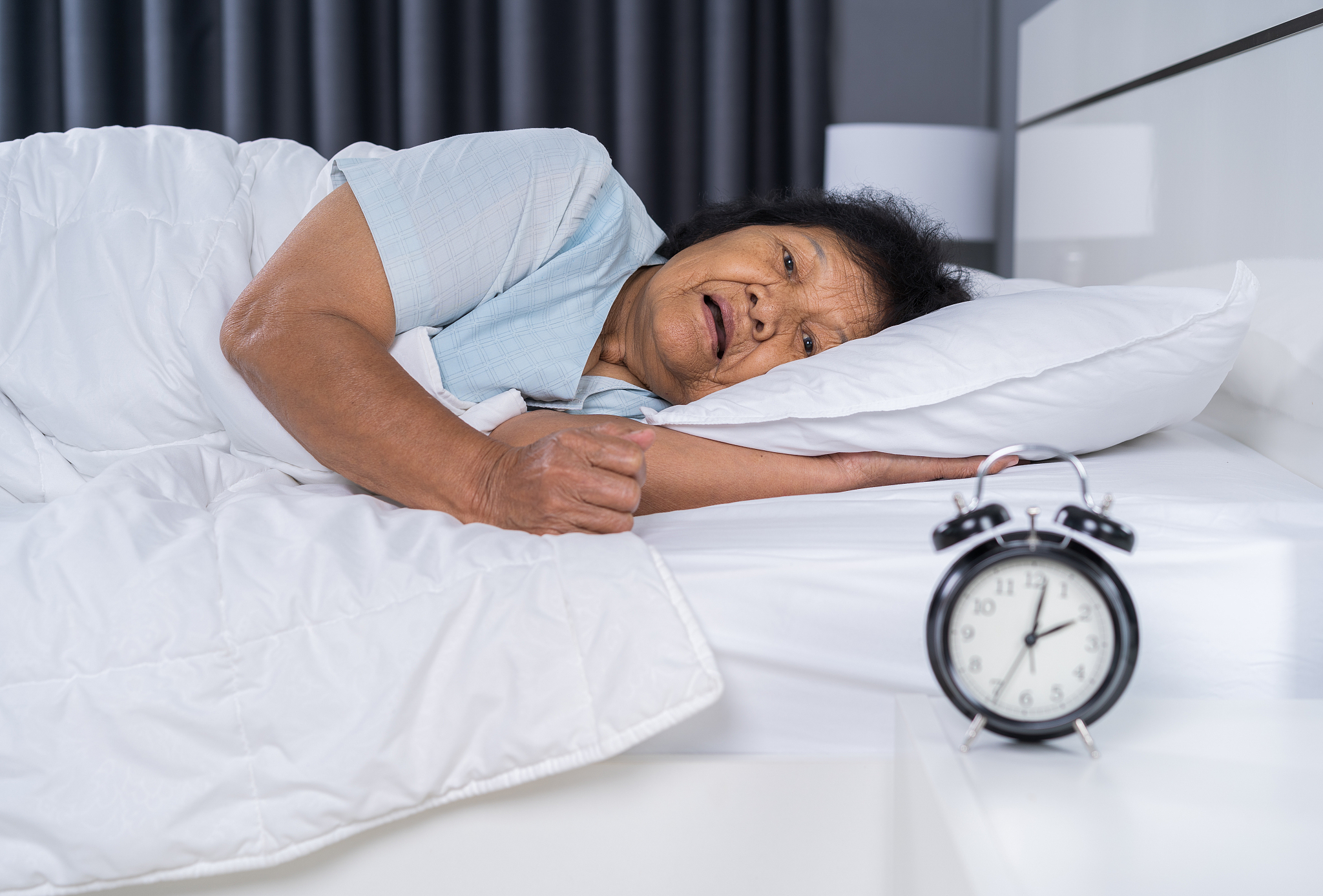 old woman suffering from insomnia is trying to sleep in bed