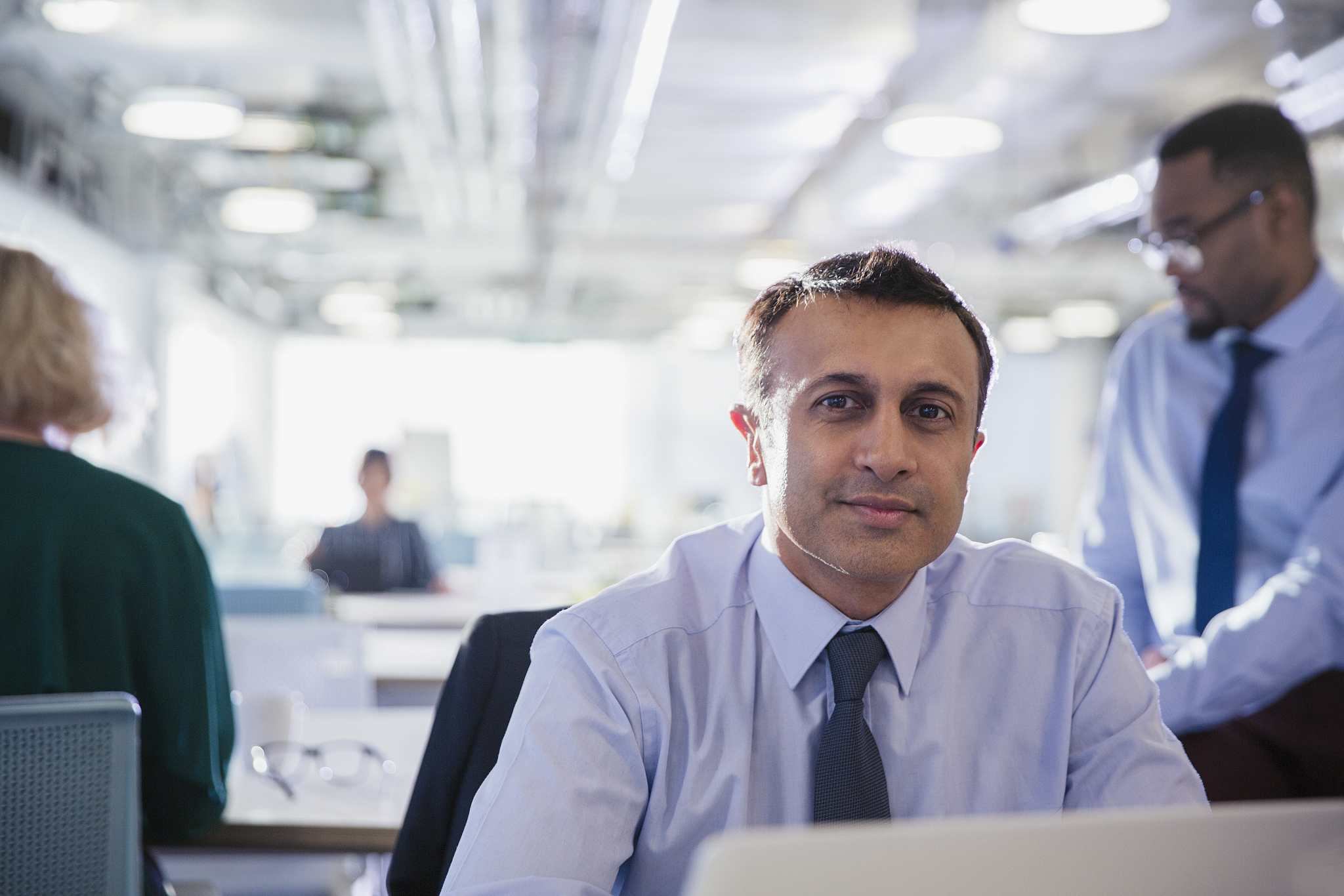 portrait confident businessman at laptop in office