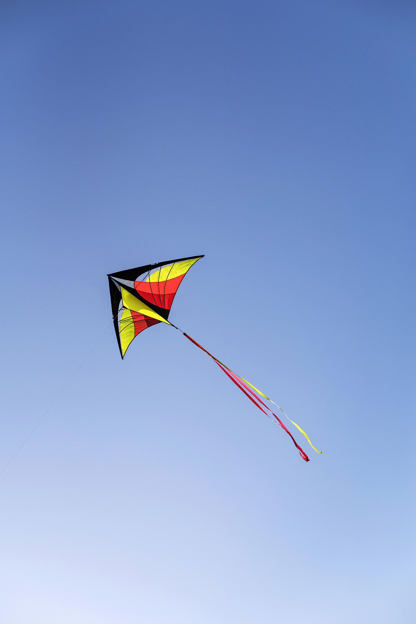 colorful kite is flying in a blue sky