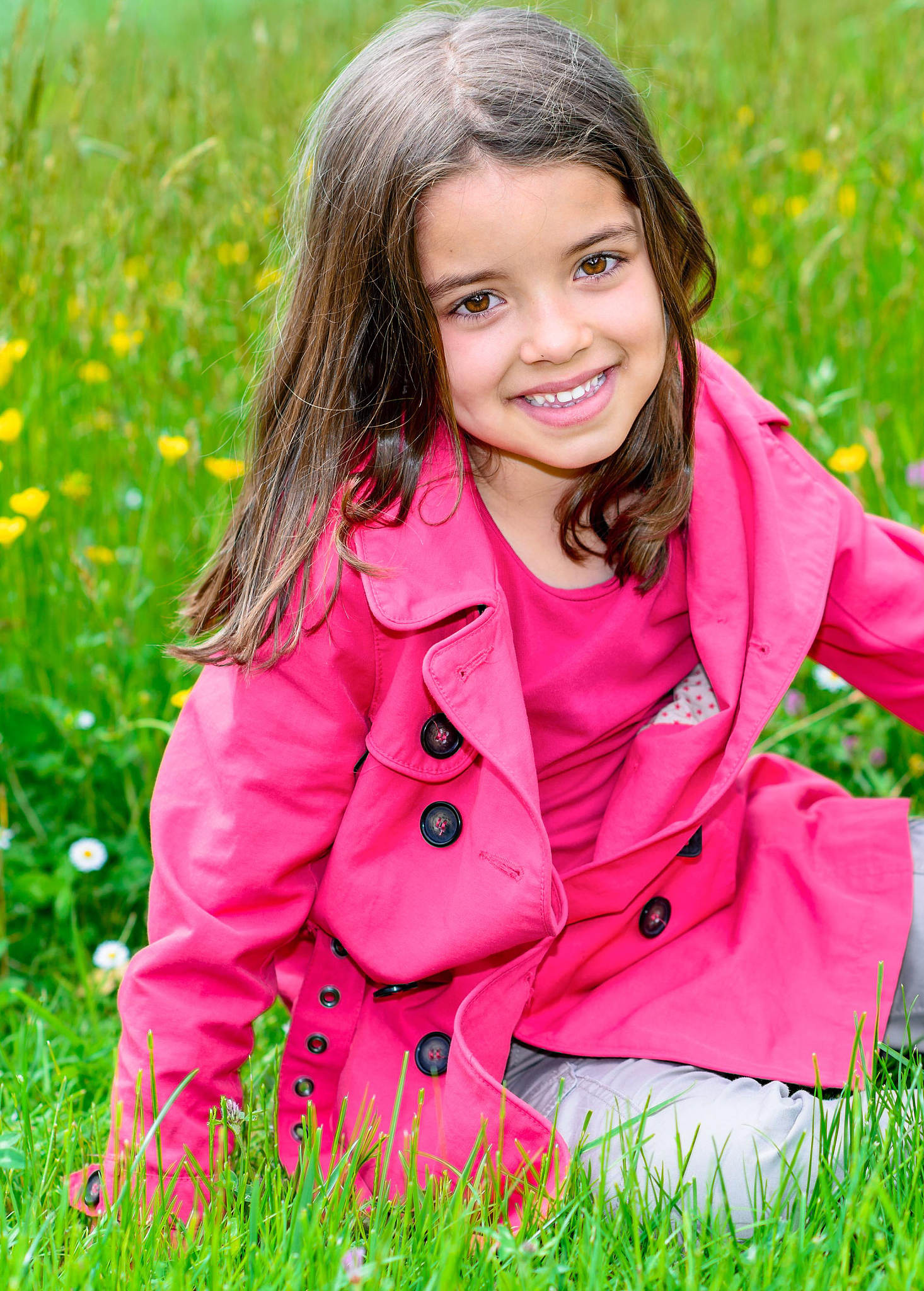 happy child sitting in a grass of a flower garden