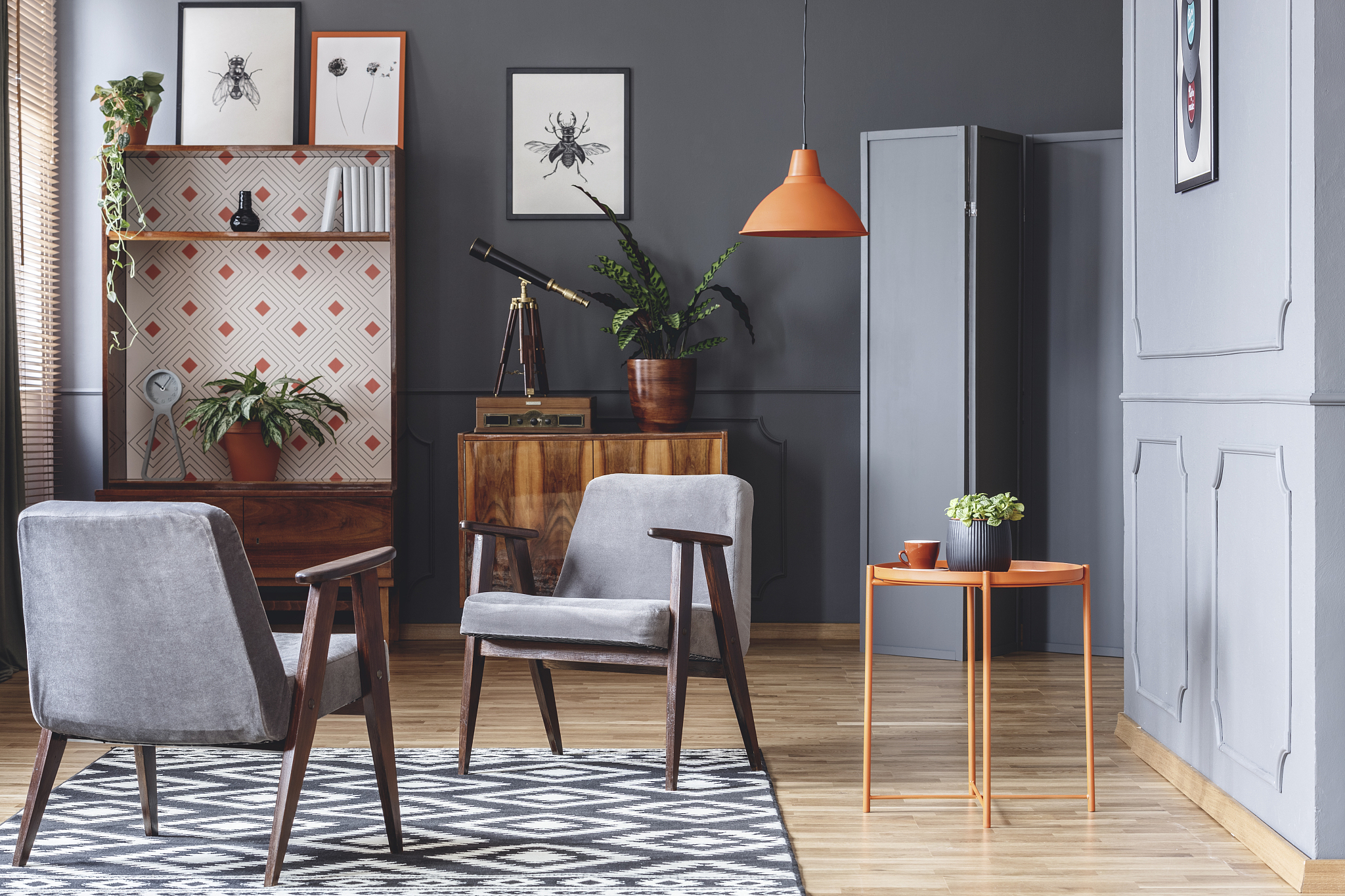 two armchairs, orange coffee table, plants, wooden cupboards and