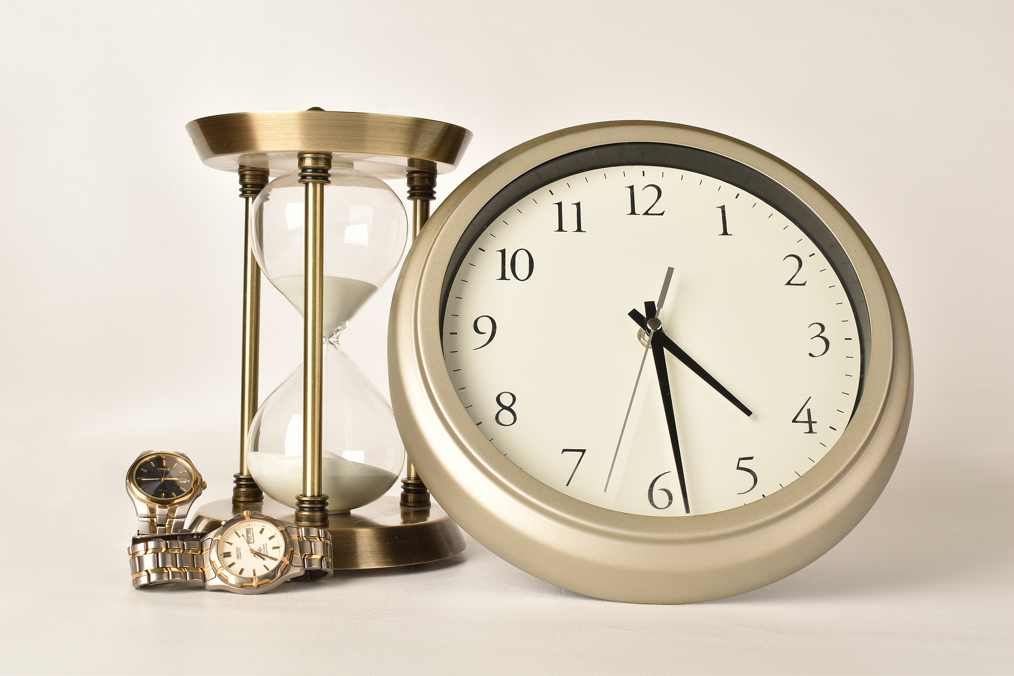 close-up of clock with hourglass against white background