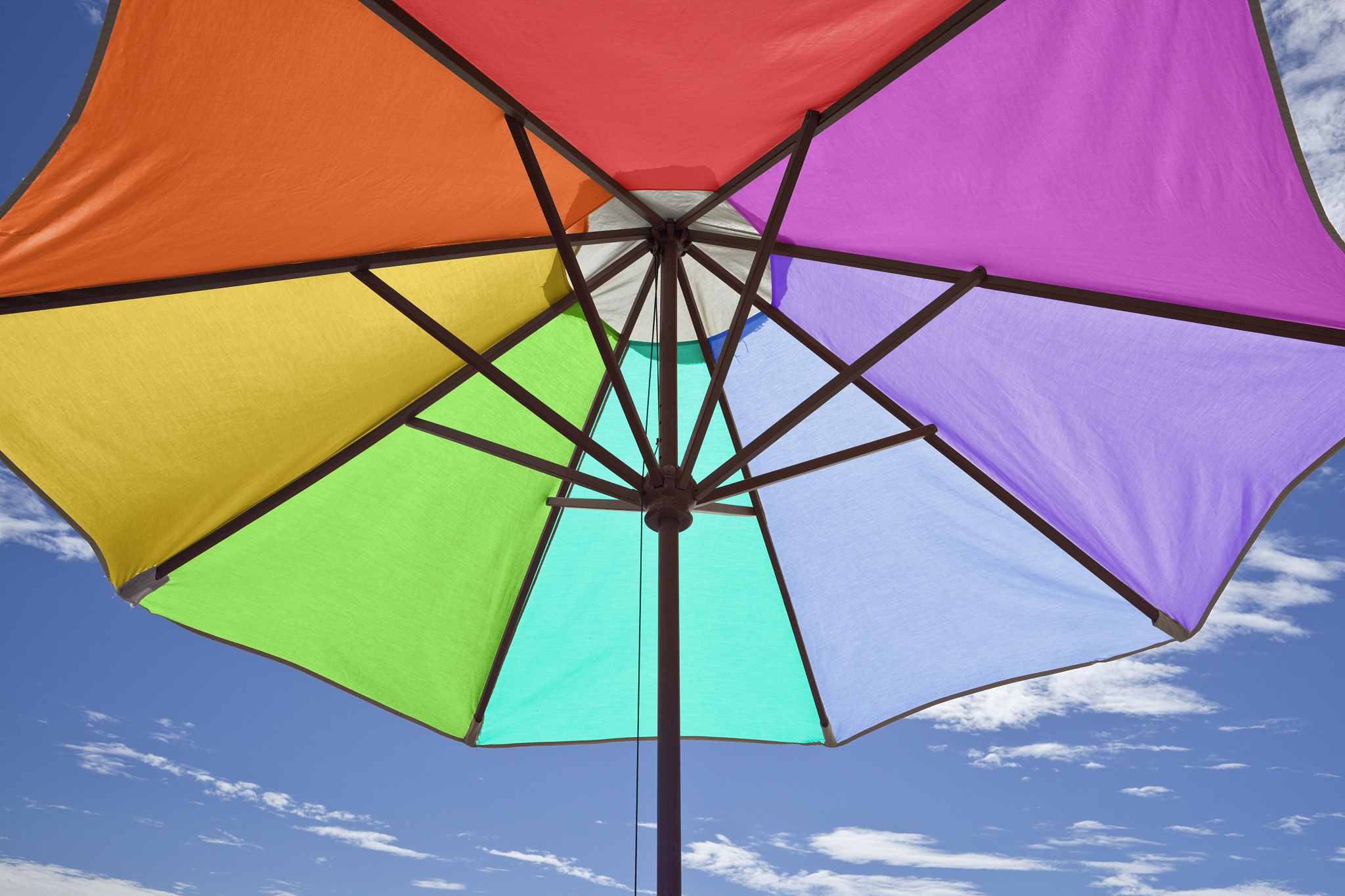 rainbow-colored beach umbrella and sunny sky