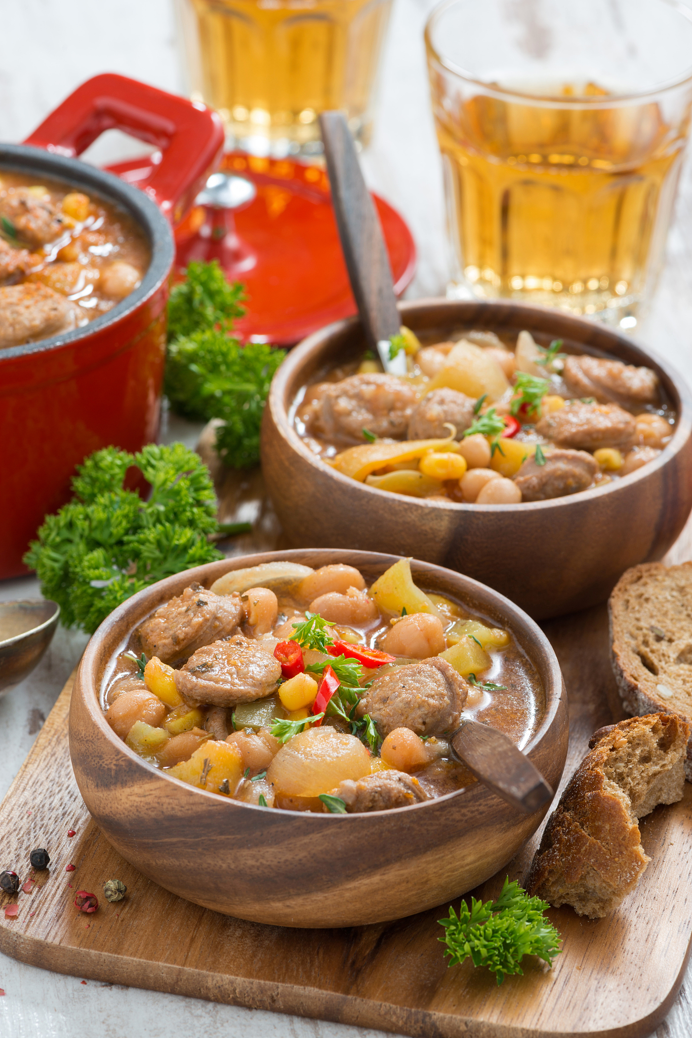 delicious vegetable stew with sausages in wooden bowl, vertical