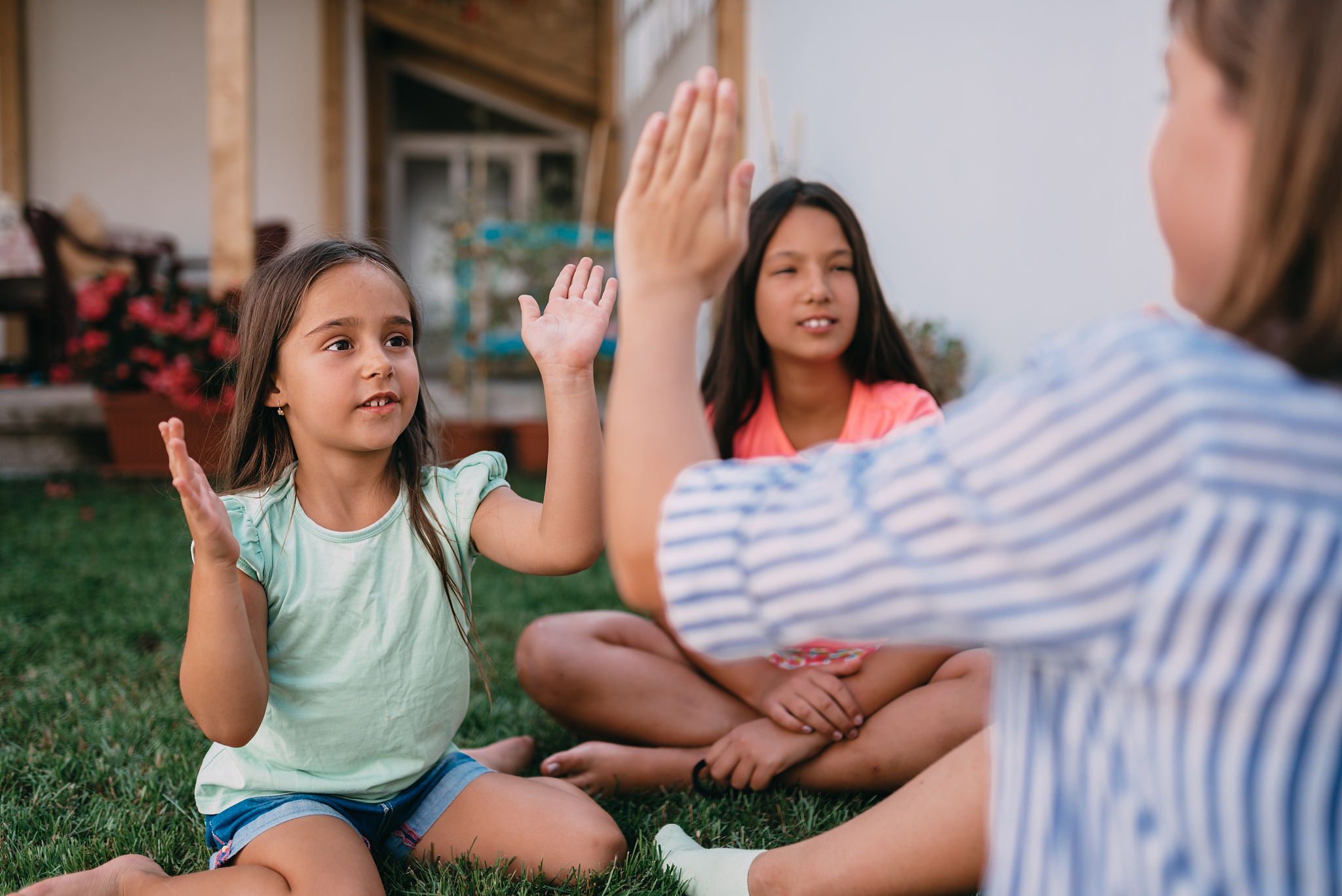 girls sitting on the grass and playing hand-clapping games