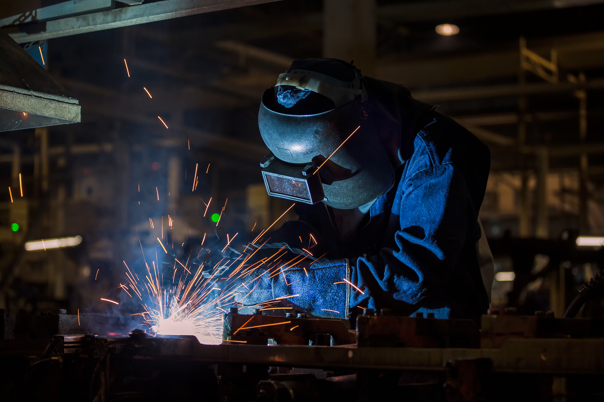 industrial worker with protective mask is welding metal part