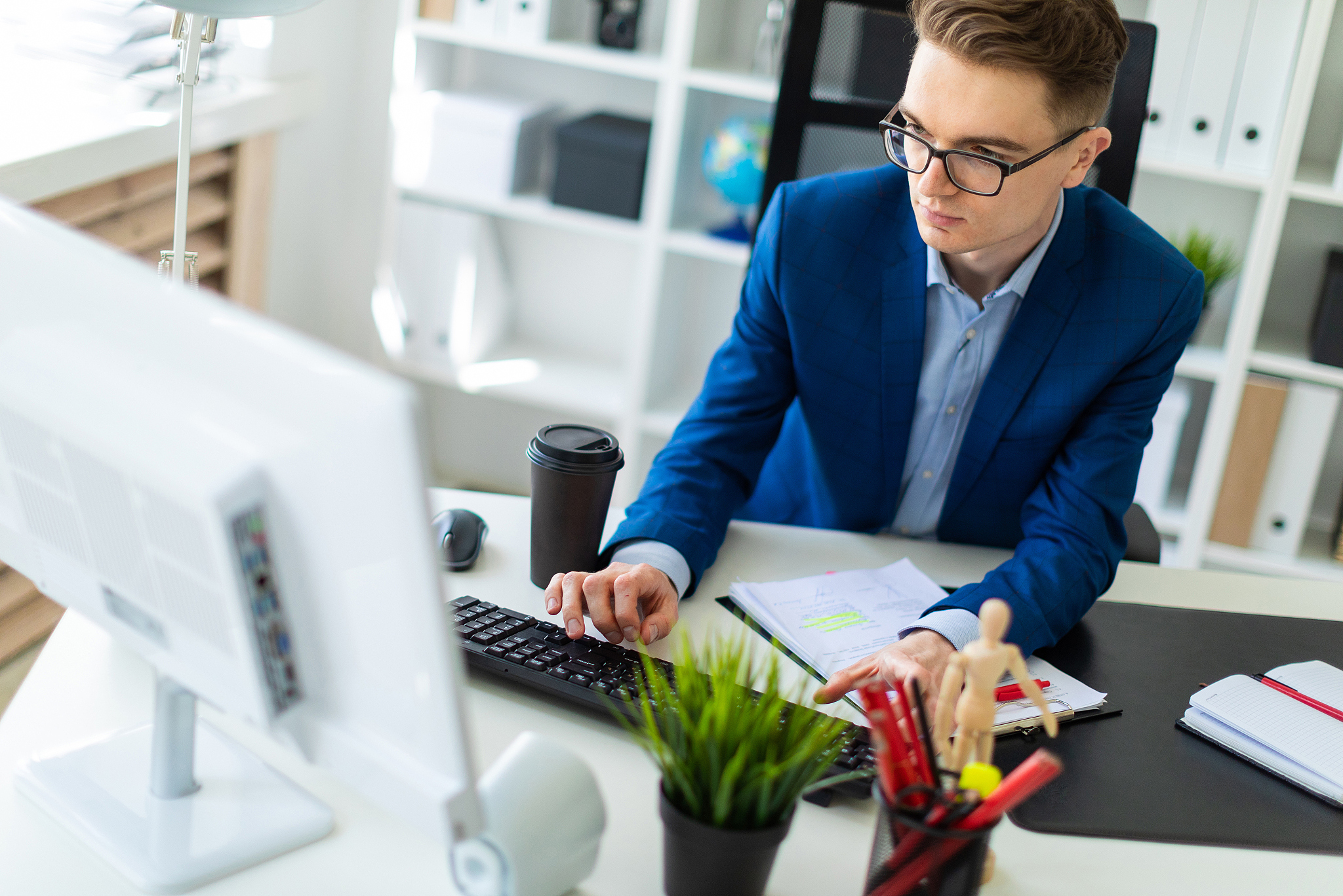 a young man sits at a table in the office and works with documen