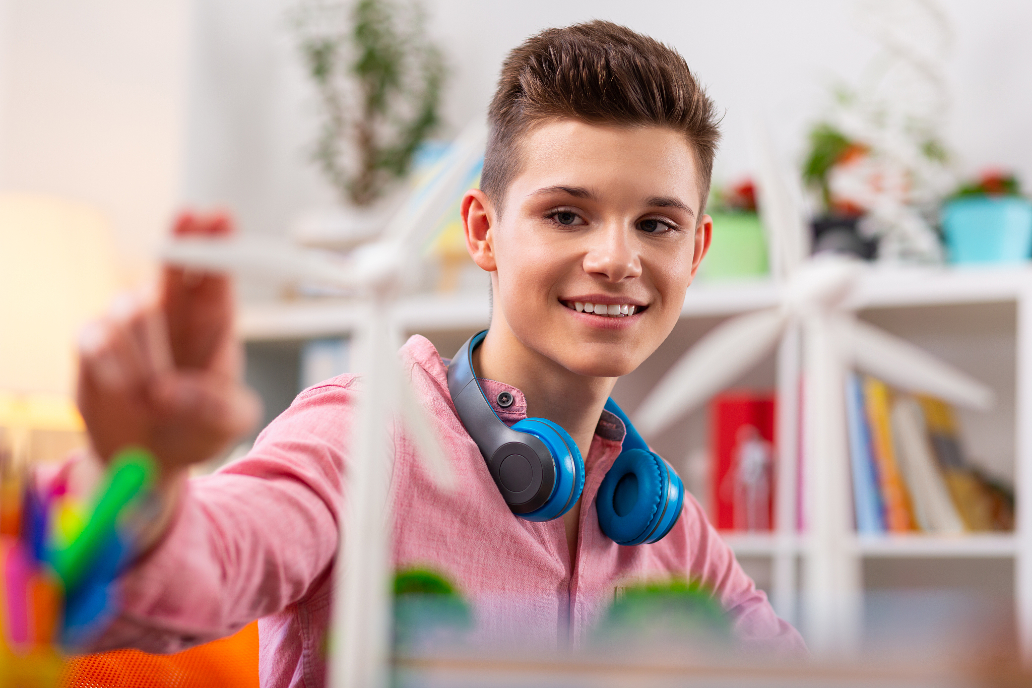 dark-eyed teenager smiling while touching model of windmill