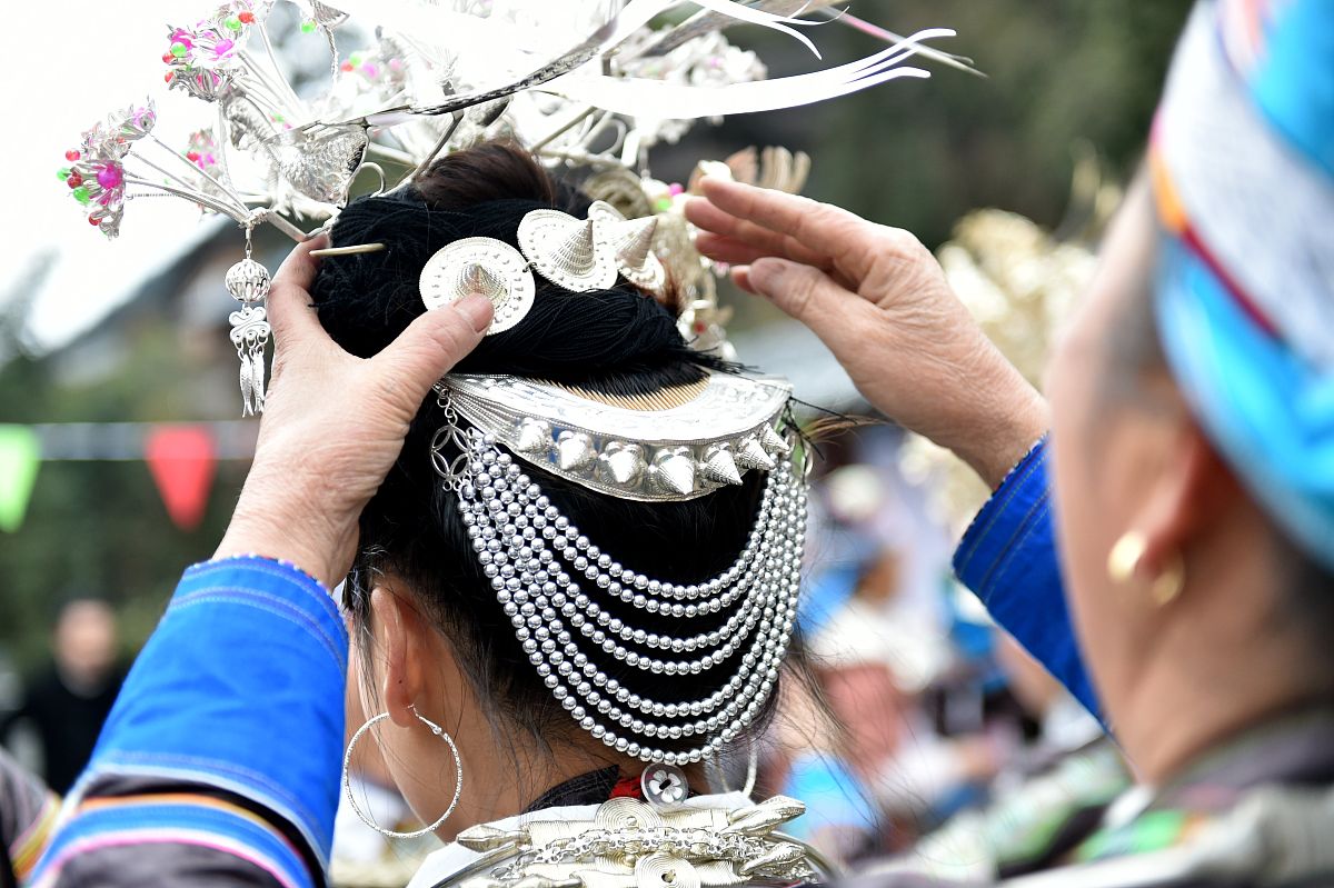2022年2月7日,在贵州省榕江县摆贝苗寨,苗族妇女在整理头饰.