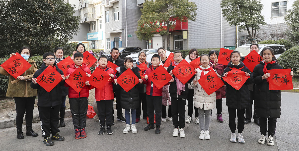 2021年12月18日,江苏淮安,小学生向社区居民赠送社会主义核心价值观作