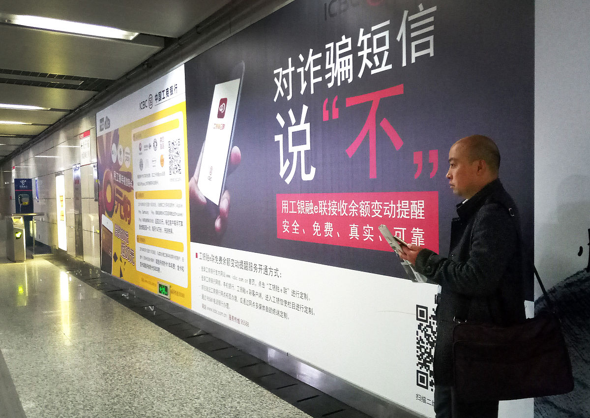 2016年11月14日,江苏省南京市,路人从地铁里一家银行"对诈骗短信说不"