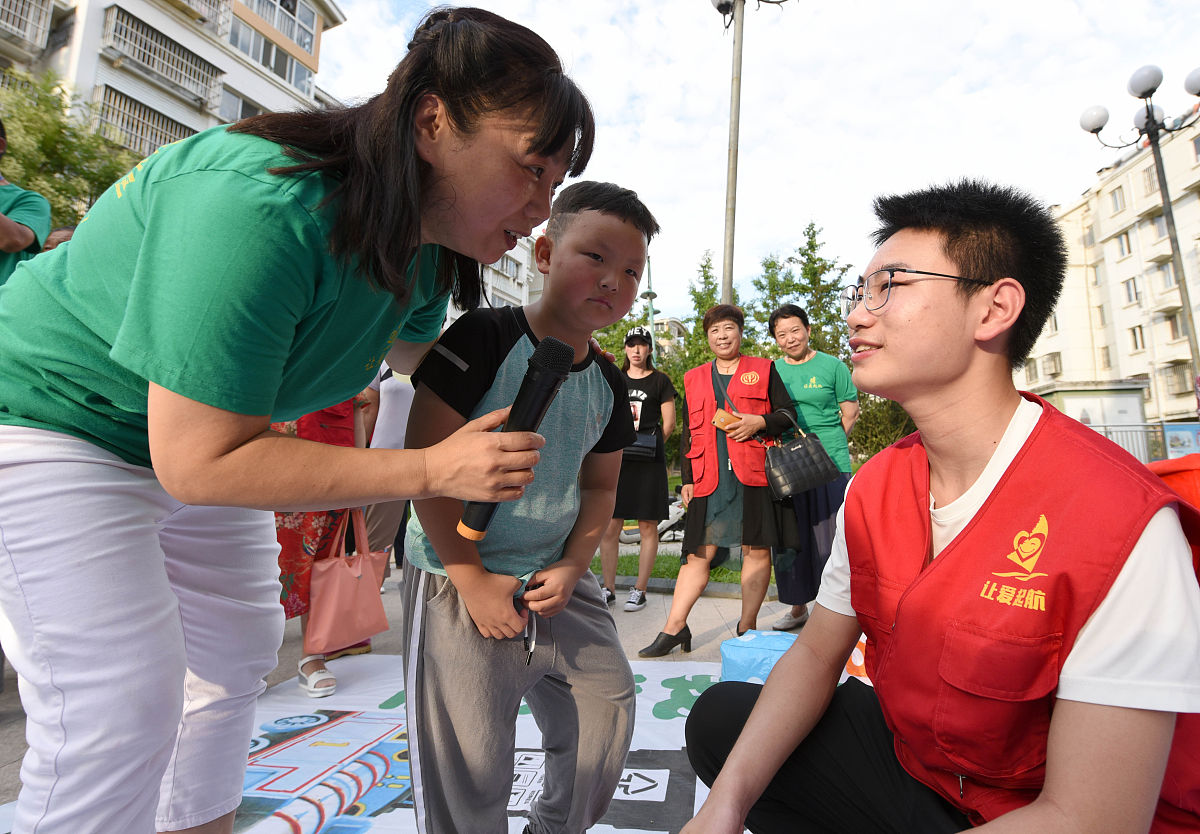 2020年8月1日,江苏淮安,志愿者向居民宣传垃圾分类知识,居民参与其中.