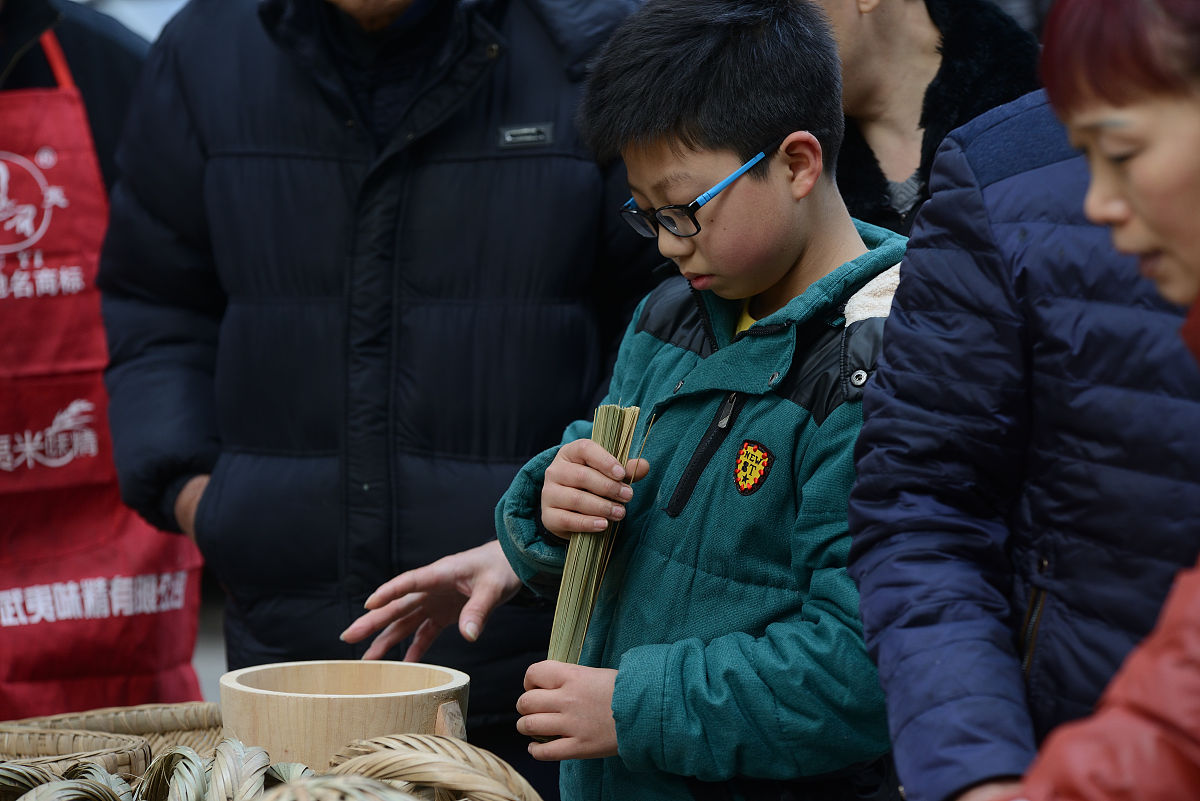 2016年2月16日,重庆.小摊旁,一个七八岁的孩童好奇地摆弄着龚师傅的作