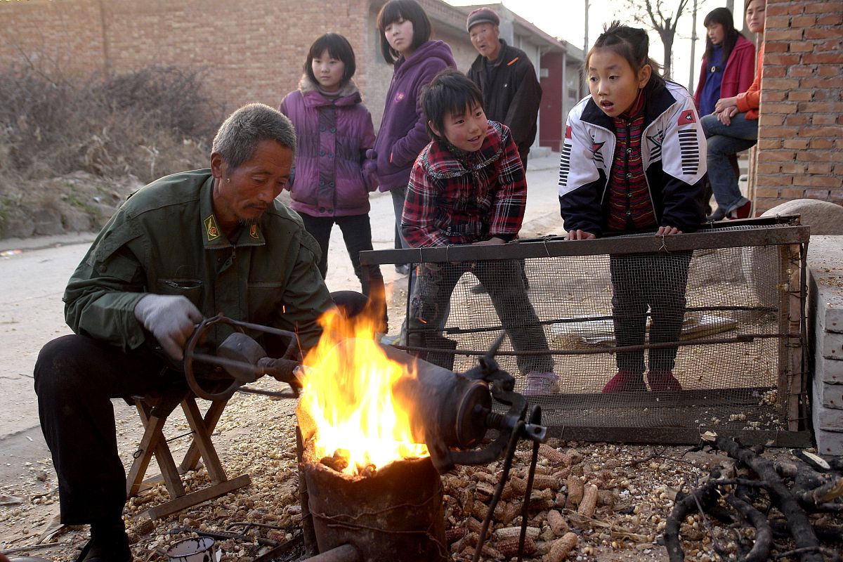 2010年12月11日,山西运城,一位手艺人正在用传统方法为乡亲爆玉米花,