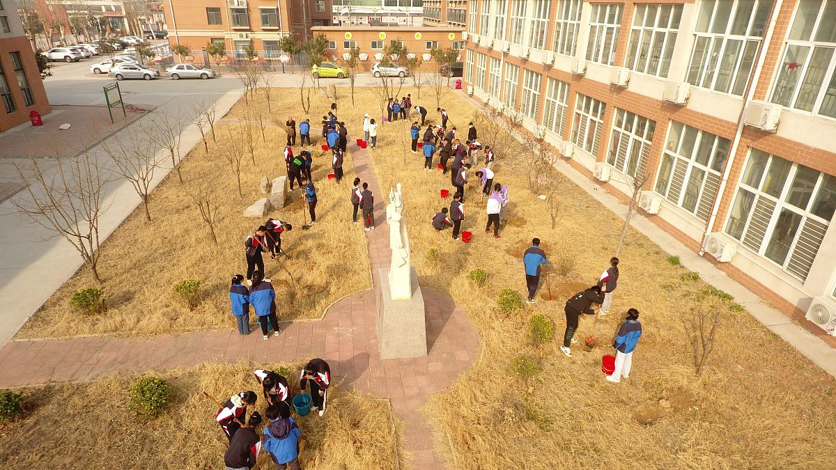 2022年3月11日,在山东省聊城市茌平区贾寨镇中学,学生们和老师一起种