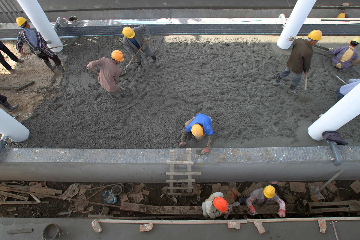 使以下句子用词更准确、具有逻辑性：在进行基础筏板混凝土的施工时需要对混凝土表面进行覆盖。覆盖时采用塑料薄膜并在其上覆盖两层草袋被草袋被需要迭缝铺放。为防止混凝土表面水分蒸发混凝土表面不应出现暴露同时薄膜内有凝结水为佳。此外需要密切关注天气情况若出现五级以上大风天气应用重物压住塑料薄膜以防止混凝土表面水分的散失。待混凝土强度养护时间达到14天并且混凝土内部与表面、混凝土表面与大气温度之差均在25℃内