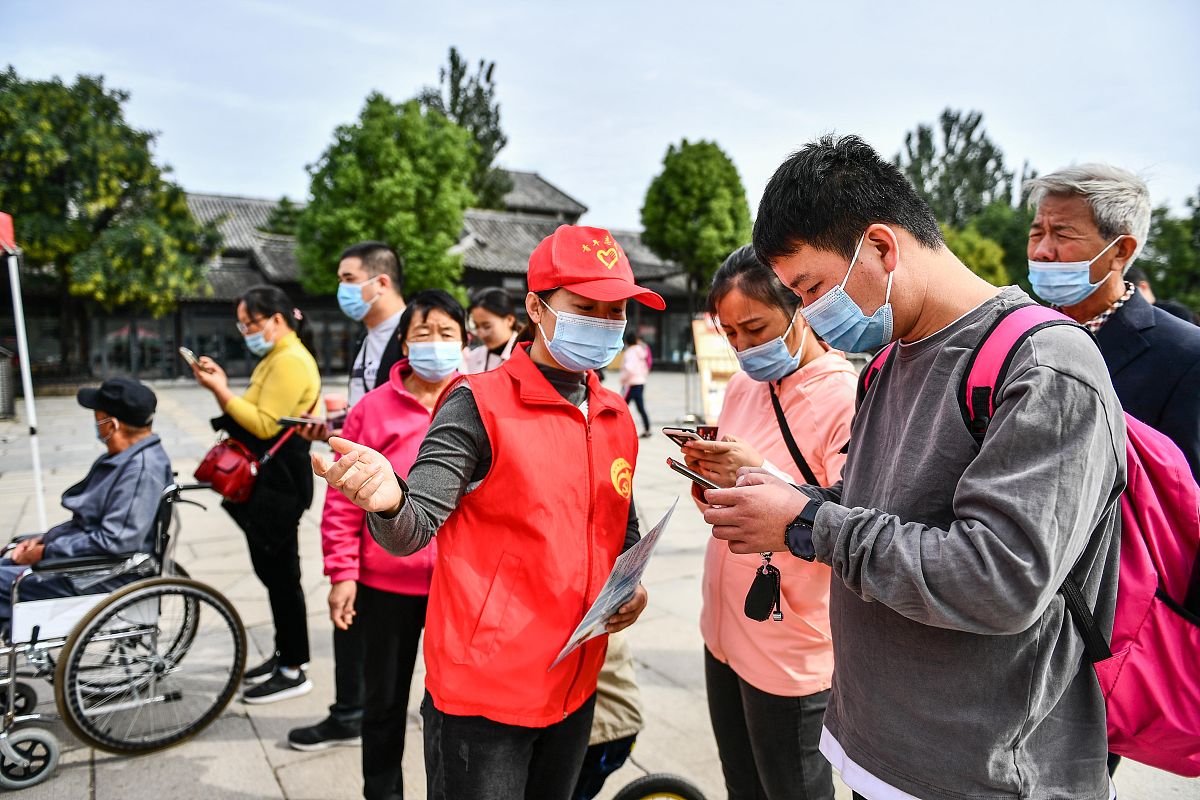 2020年10月5日,在山东省枣庄市台儿庄古城景区入口处,志愿者为游客提