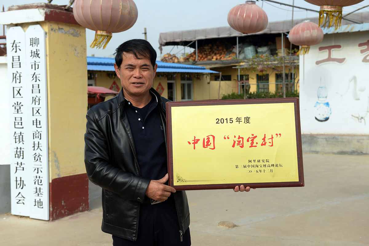 2018年村民郝洪燃在展示"中国淘宝村"的牌子.