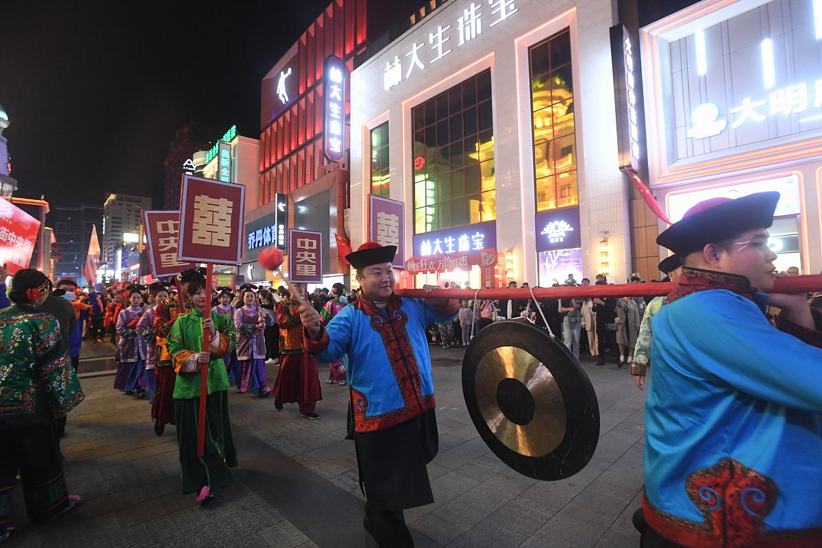 2021年10月2日,沈阳中央里满族大院办喜事,游人参与助兴.