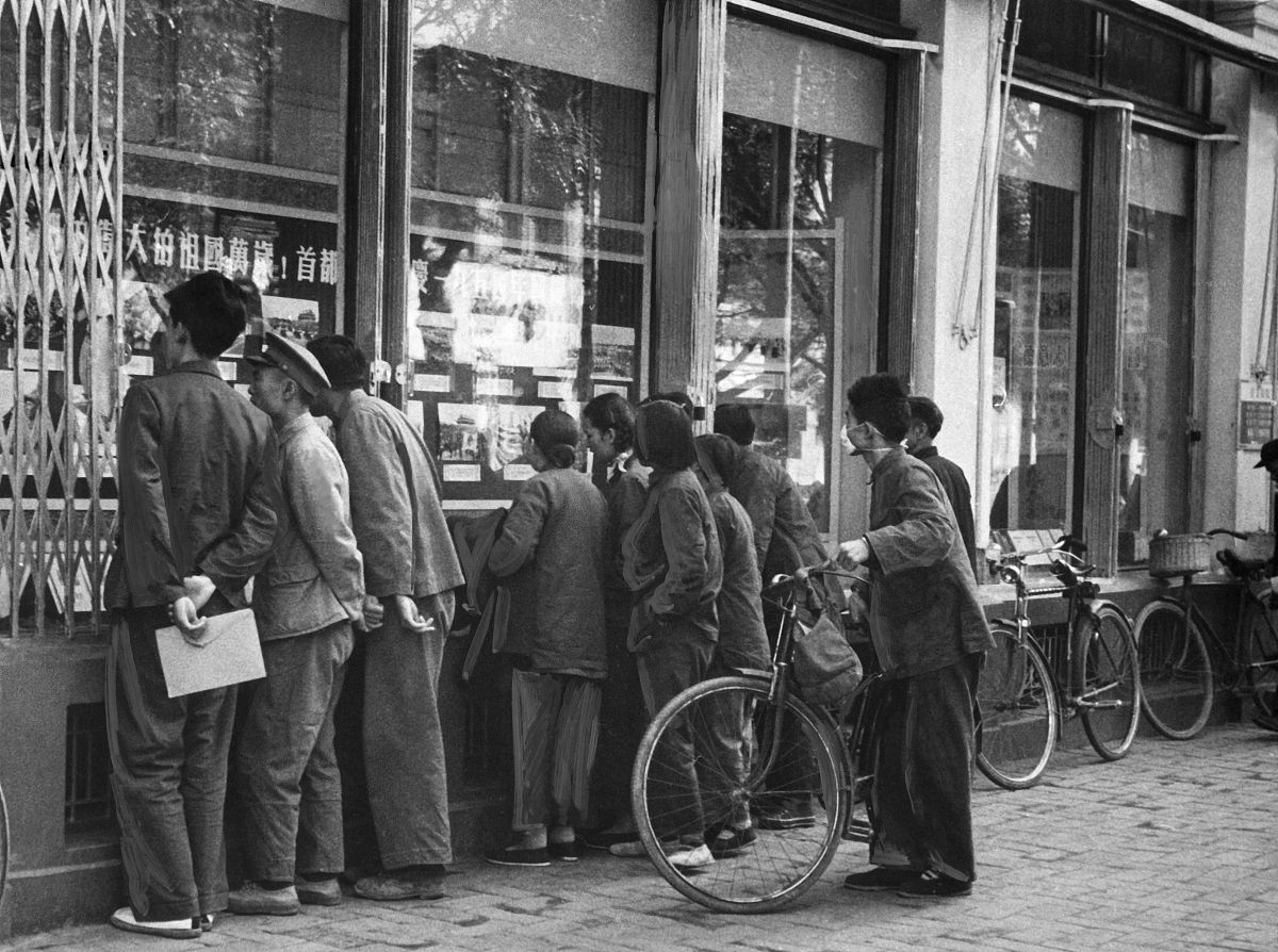1950年代,北京,行人们观看一家商店橱窗中张贴的照片.passants regard