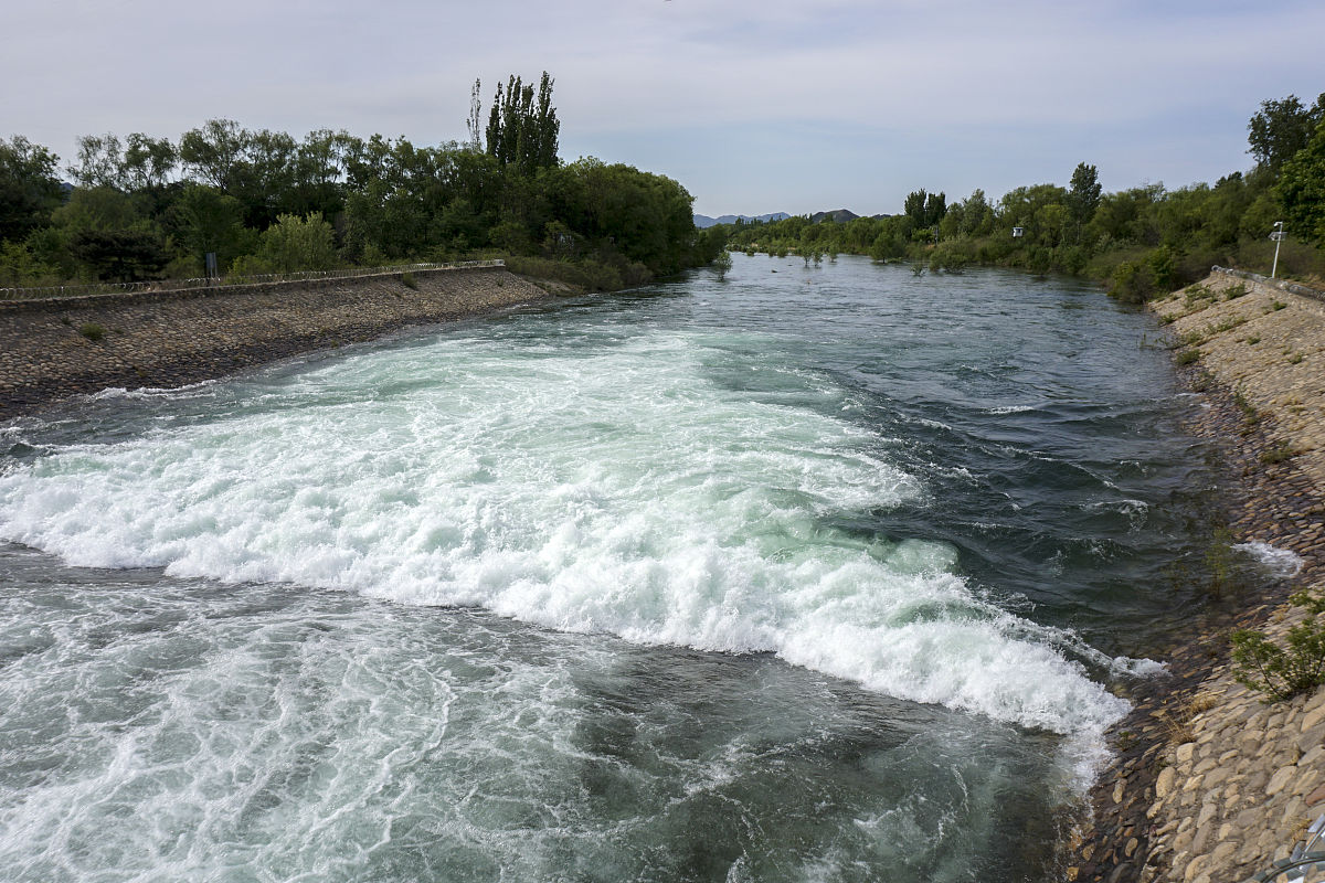 假设在一座宽阔且水深很深的湖里我想通过构筑堤坝的方式在靠近湖案的某一块区域使水流速加快从而制造出水浪这个堤坝应该怎么做？