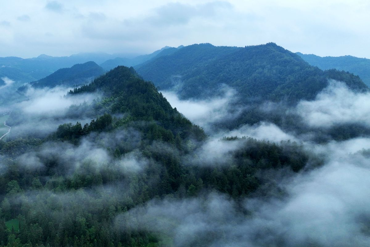 请用100字形容一下房子后远山云雾环绕的场景