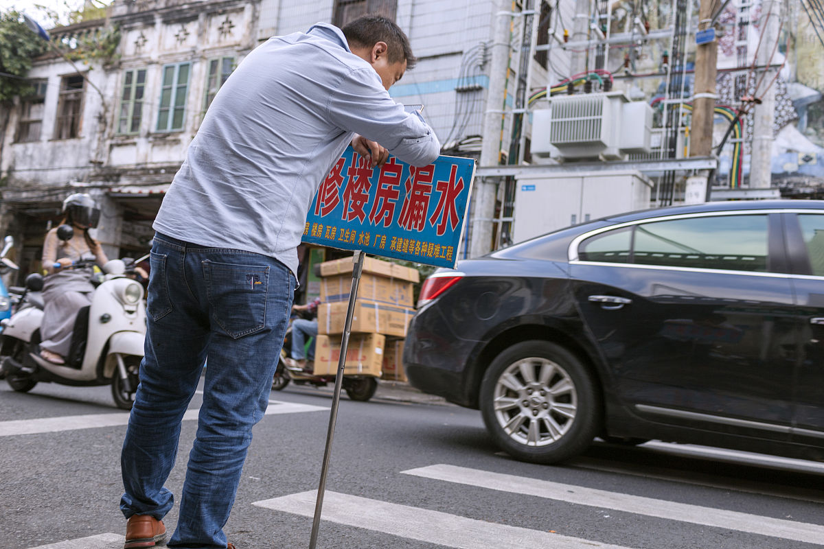 2019年11月27日,海口, 博爱路老街上一位撑着牌子揽活的男人.