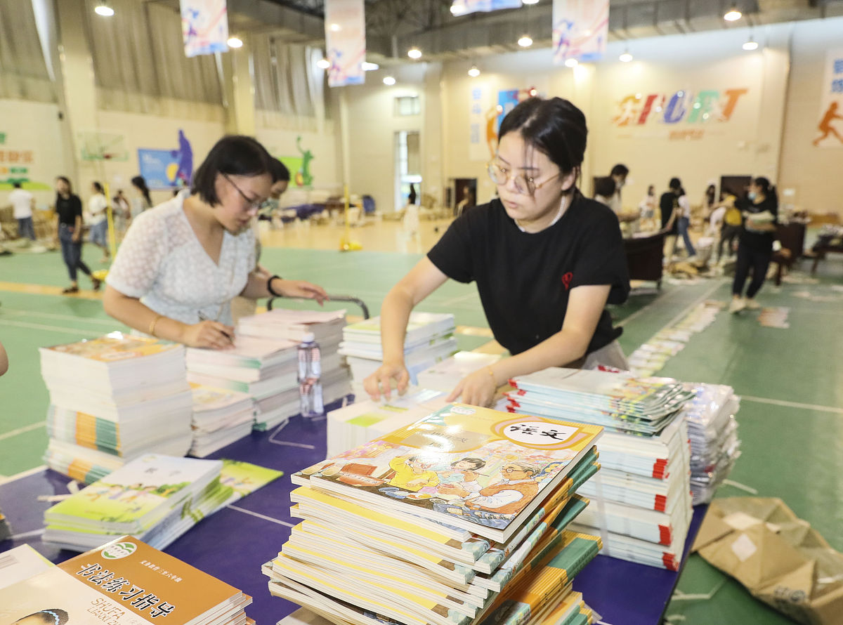 2021年8月29日,江苏淮安,老师在学校分发新学期教材.