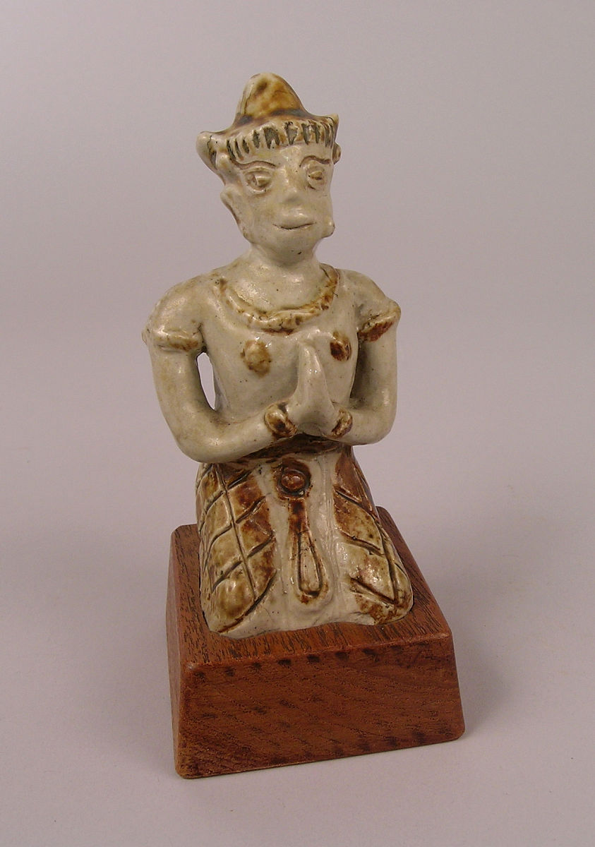 figure on his knees with hands raised to the chest in a position